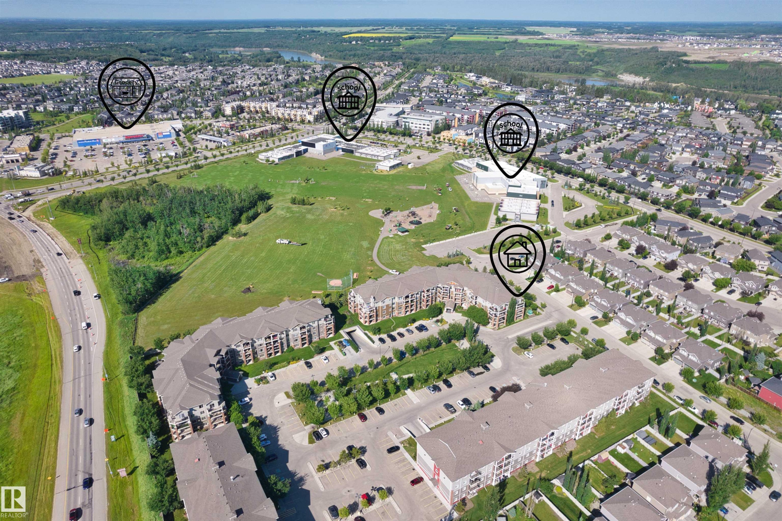 Aerial perspective showcasing a developed community with residential buildings, commercial structures, and green spaces - #317 3719 Whitelaw Ln Nw, Edmonton, AB - Outdoor With View