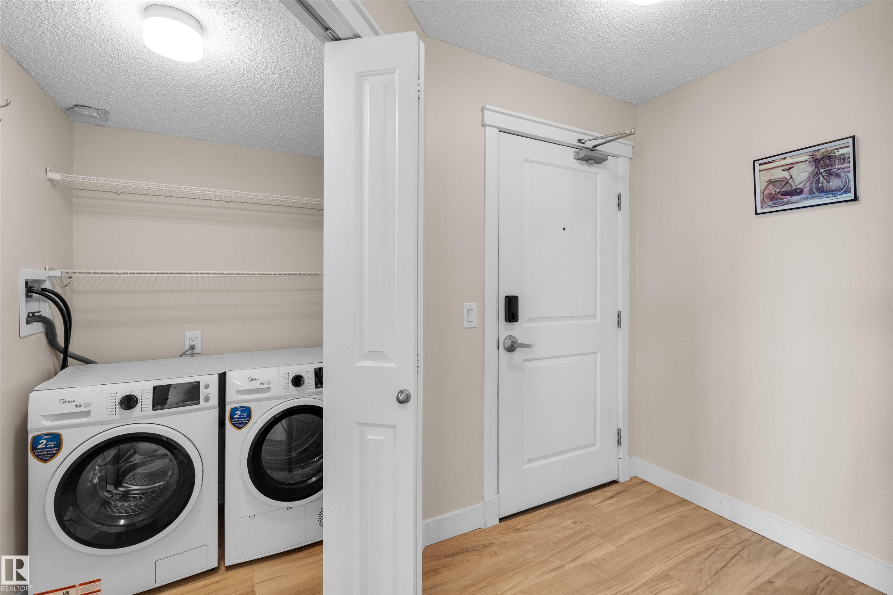 Dedicated laundry area with front-loading washer and dryer, complemented by wire shelving for storage - #317 3719 Whitelaw Ln Nw, Edmonton, AB - Indoor Photo Showing Laundry Room