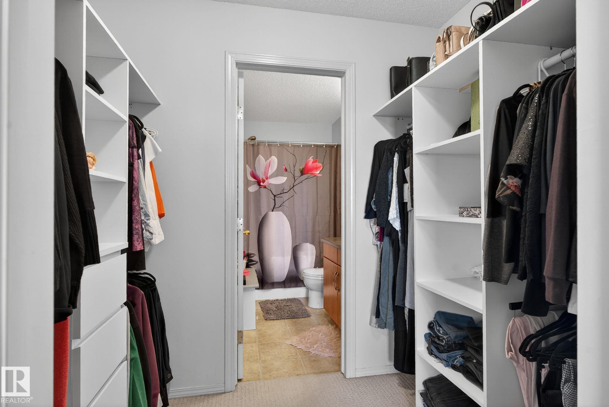 Walk-in closet featuring white built-in shelving, hanging rods, and integrated drawers - 423 2430 Guardian Road, Edmonton, AB - Indoor With Storage