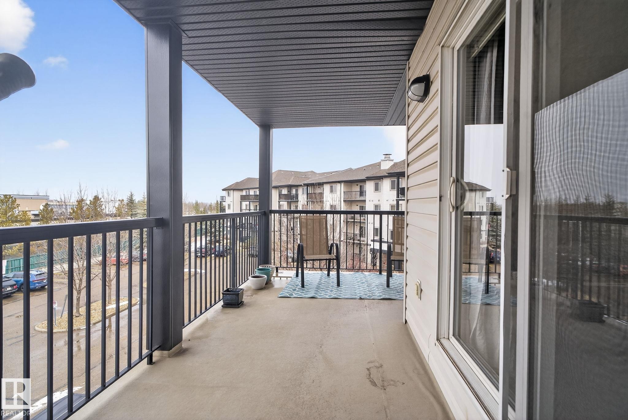 Private balcony featuring a concrete floor, black metal railing, and a sliding glass door with screen - 423 2430 Guardian Road, Edmonton, AB - Outdoor With Balcony With Exterior