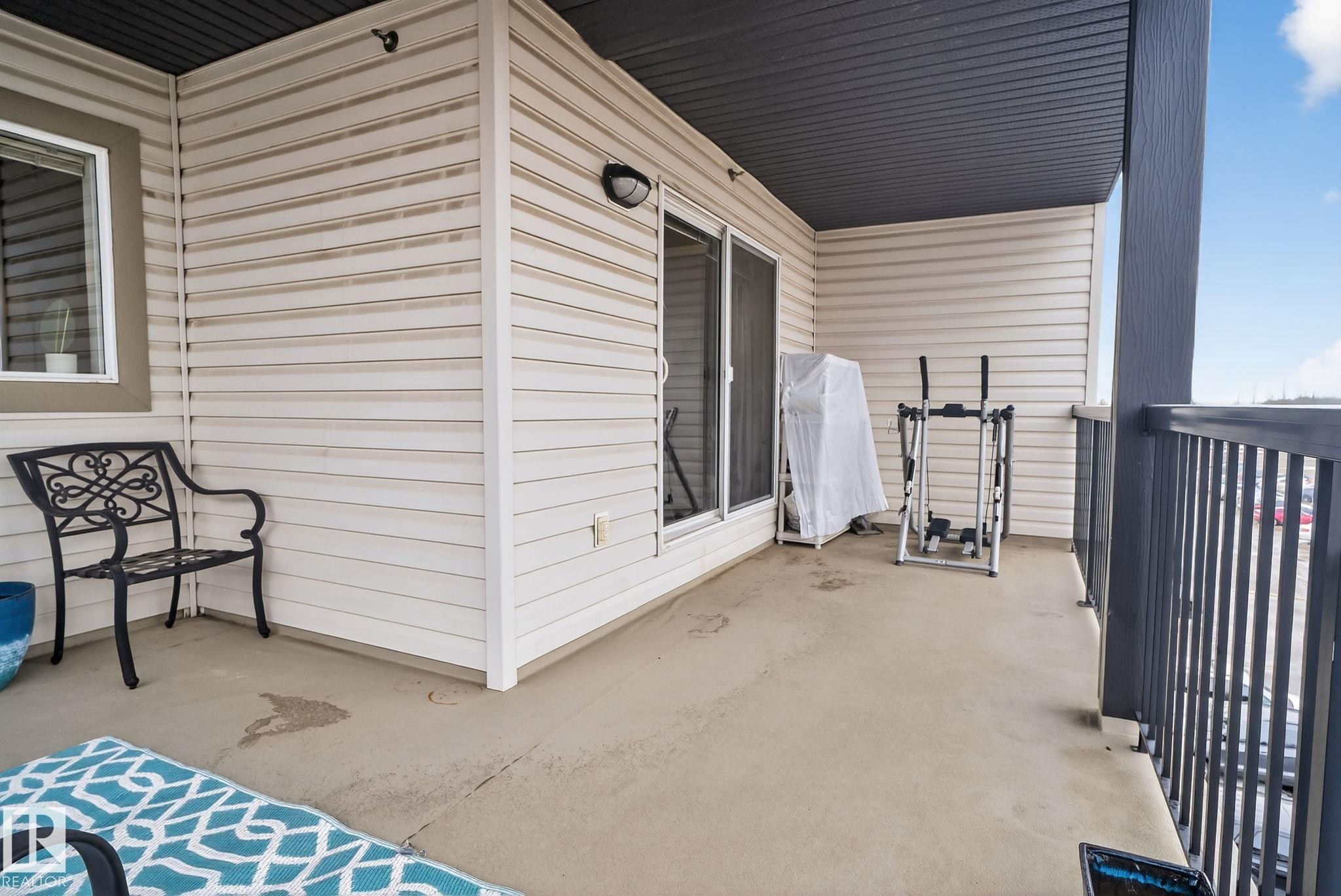 Outdoor balcony featuring a concrete surface, white horizontal siding, and a dark grey ceiling - 423 2430 Guardian Road, Edmonton, AB - Outdoor With Exterior