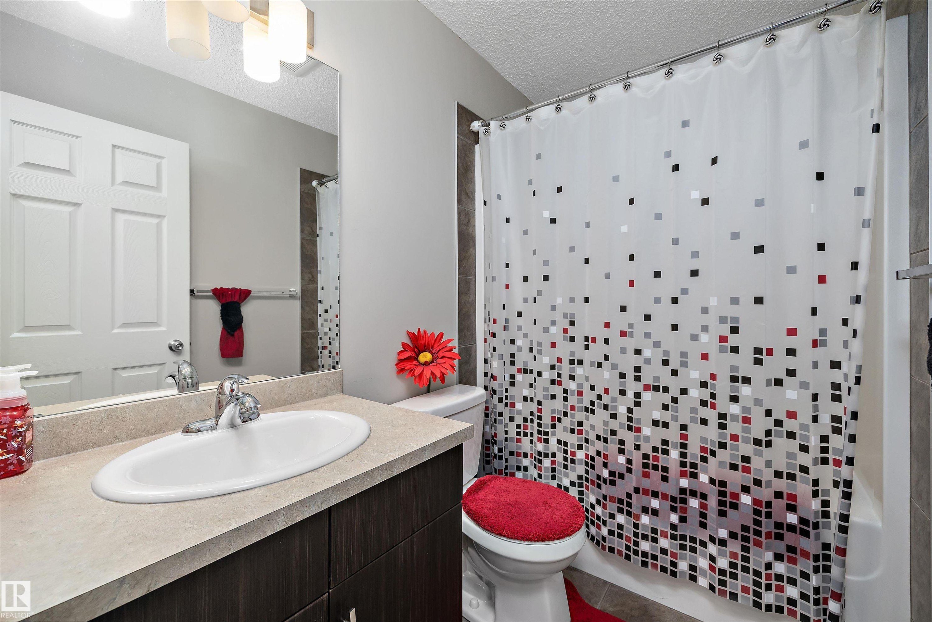 Bathroom vanity featuring a light-toned countertop, undermount sink, and dark wood-finish cabinetry - 4688 Crabapple Run Sw, Edmonton, AB - Indoor Photo Showing Bathroom