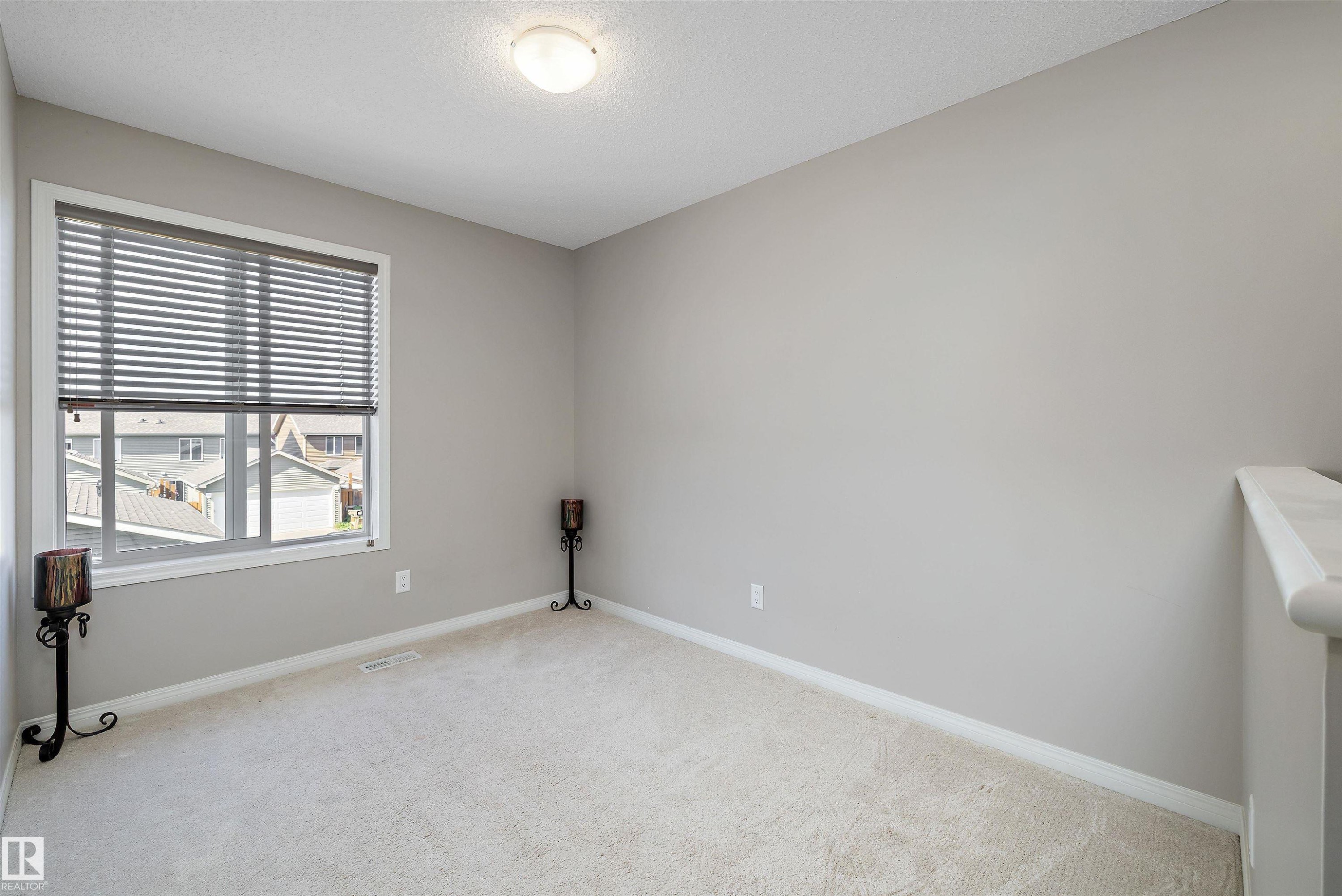 Neutral-toned room featuring a large window with horizontal blinds, providing natural illumination - 4688 Crabapple Run Sw, Edmonton, AB - Indoor Photo Showing Other Room