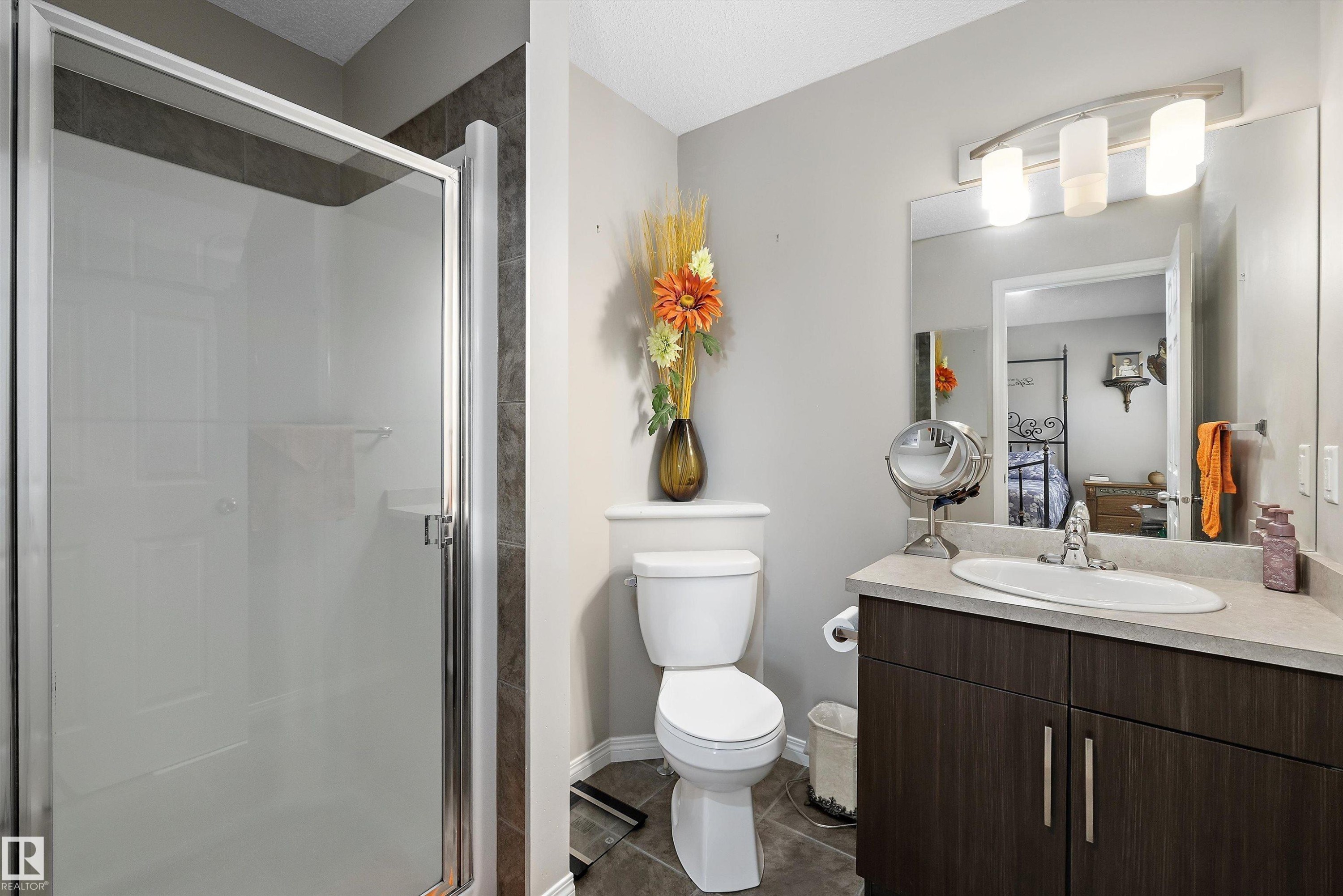 Bathroom featuring a glass-enclosed shower, a vanity with a built-in sink, a large mirror, and tiled flooring - 4688 Crabapple Run Sw, Edmonton, AB - Indoor Photo Showing Bathroom