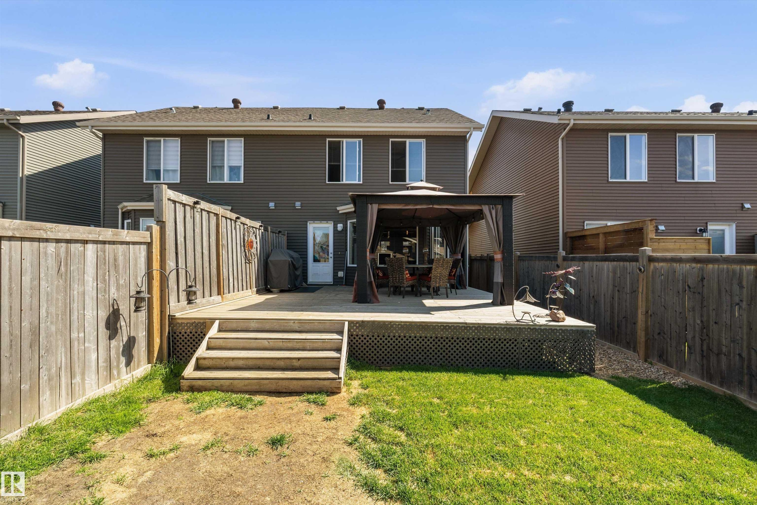 Expansive backyard featuring a large wooden deck with integrated steps, a privacy fence, and a spacious lawn area - 4688 Crabapple Run Sw, Edmonton, AB - Outdoor With Deck Patio Veranda With Exterior