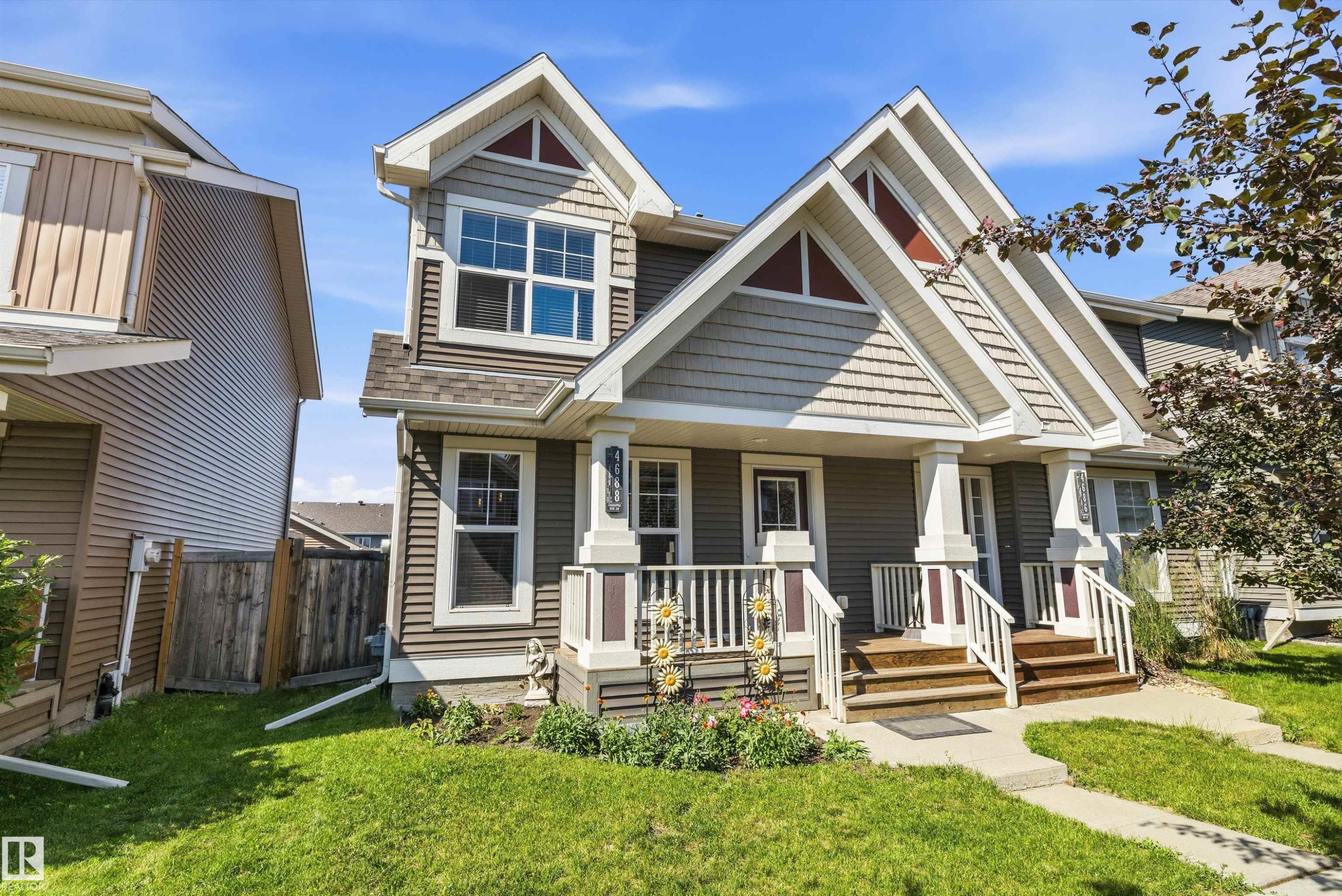 Two-story exterior with multi-toned siding, a prominent gabled roofline, and a covered front porch featuring white railings - 4688 Crabapple Run Sw, Edmonton, AB - Outdoor With Facade