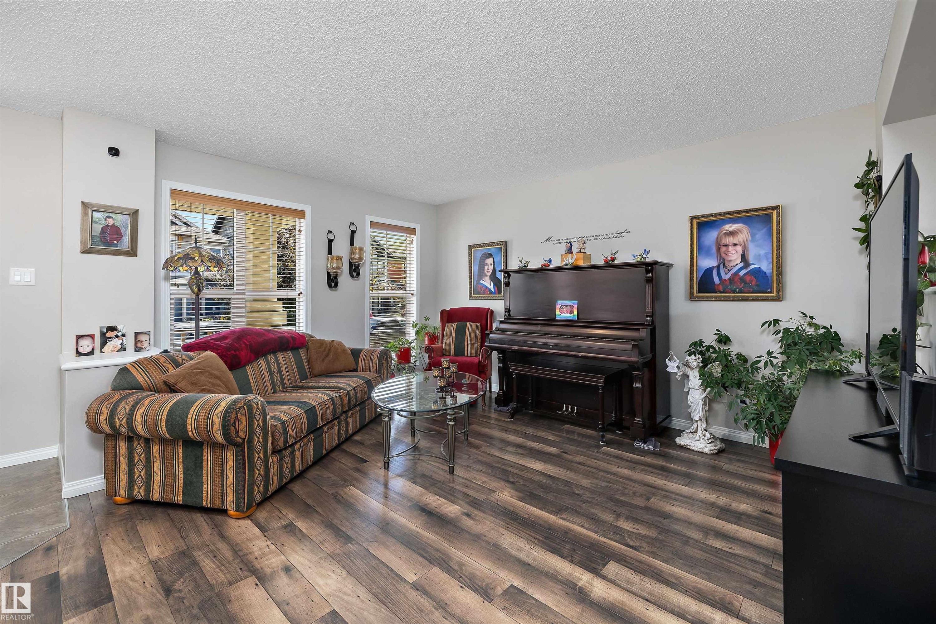 Spacious living area featuring wood-finish flooring, light grey wall tones, and multiple windows with blinds - 4688 Crabapple Run Sw, Edmonton, AB - Indoor Photo Showing Living Room