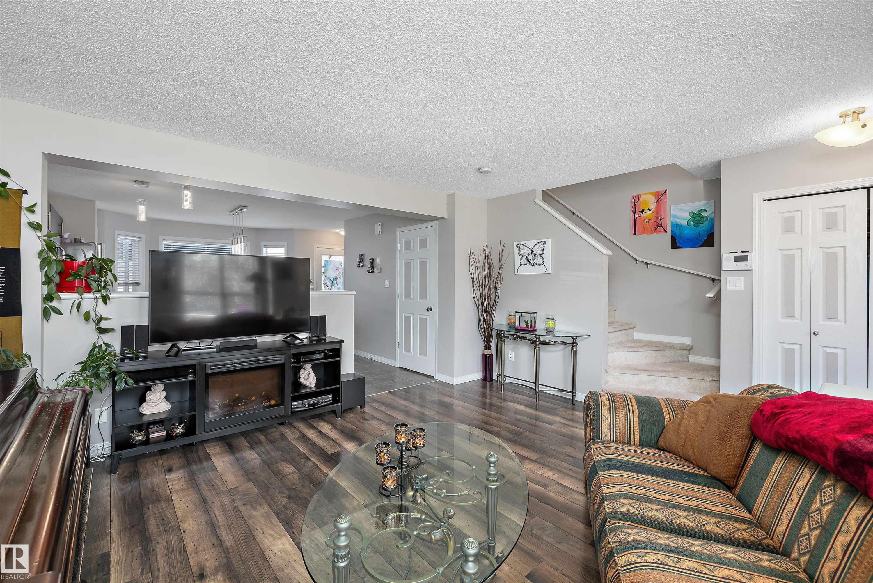 Open-concept living space featuring wood-finish flooring, a built-in electric fireplace, and light grey wall paint - 4688 Crabapple Run Sw, Edmonton, AB - Indoor Photo Showing Living Room
