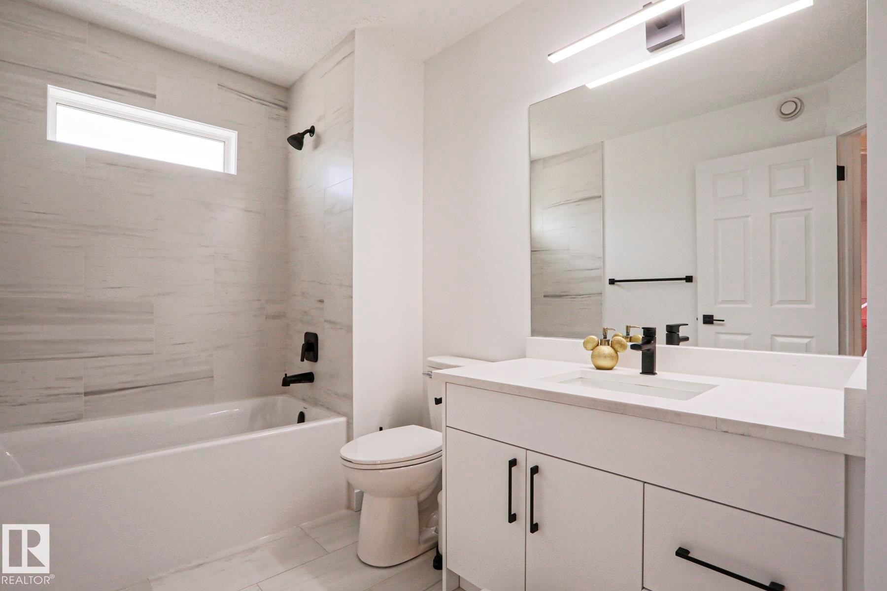 Modern bathroom featuring a white vanity with integrated sink and matte black fixtures - 11347 10 Avenue, Edmonton, AB - Indoor Photo Showing Other Room