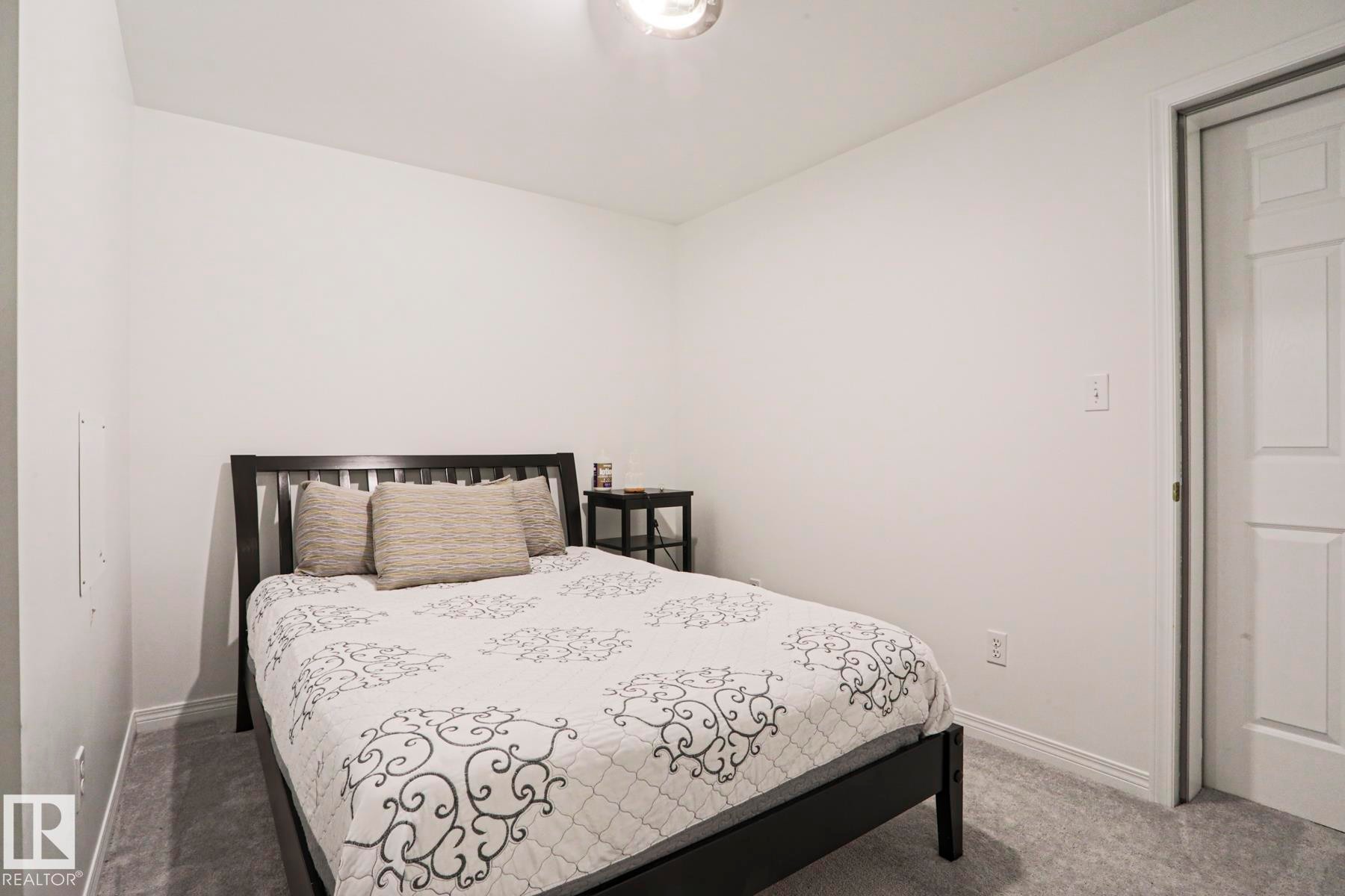 White walls, gray carpet flooring, white baseboards, and a white interior door - 11347 10 Avenue, Edmonton, AB - Indoor Photo Showing Basement