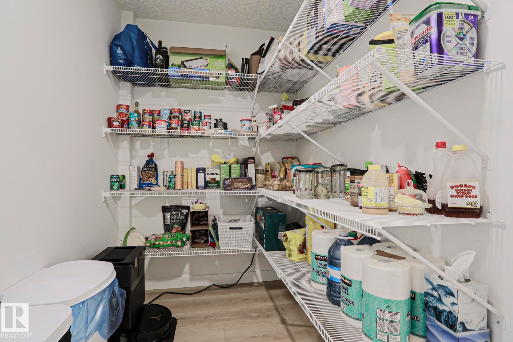 Walk-in pantry featuring white wire shelving, light wood-finish flooring, and white painted walls - 11347 10 Avenue, Edmonton, AB - Indoor With Storage