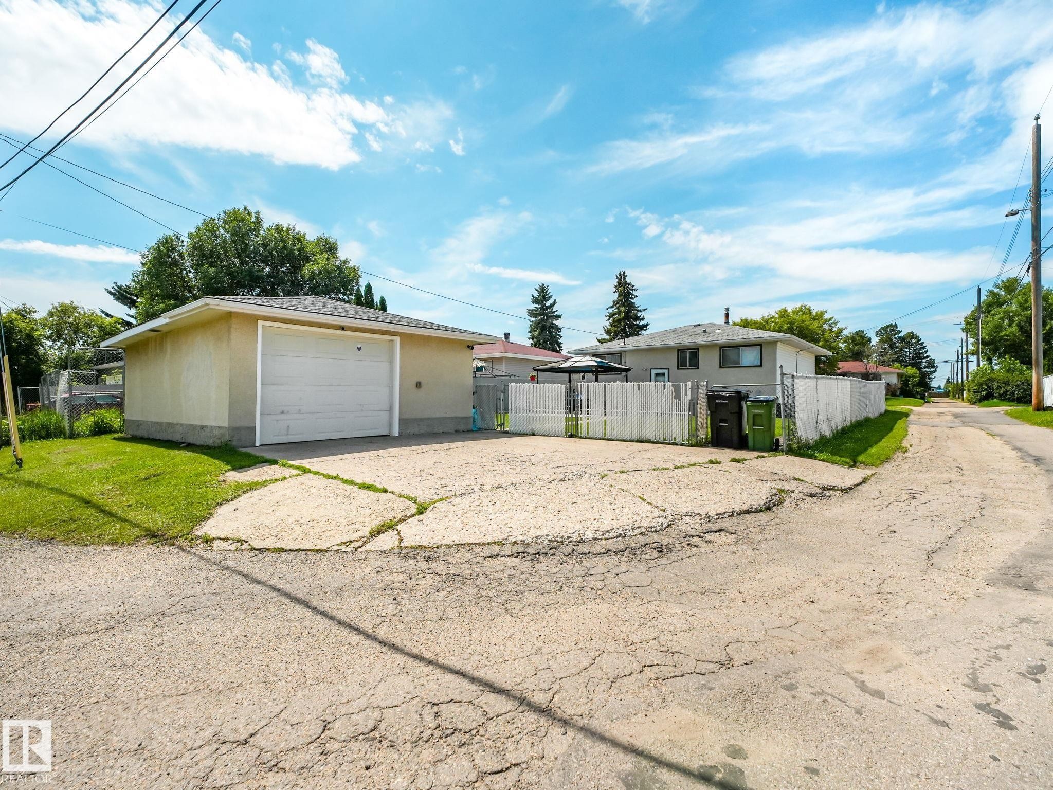 Detached garage with a white overhead door and shingle roof, set on a concrete pad - 13323 58 Street Nw, Edmonton, AB - Outdoor