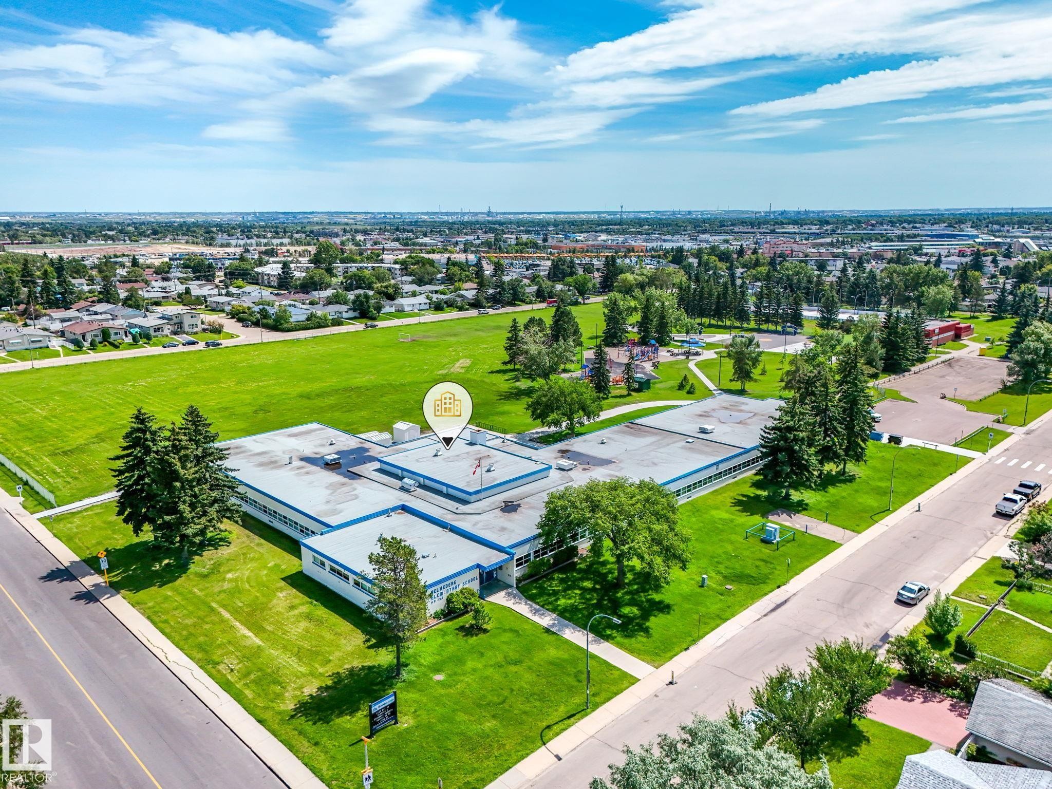 Expansive property featuring a large institutional building with a flat roof and numerous windows, surrounded by vast green spaces - 13323 58 Street Nw, Edmonton, AB - Outdoor With View