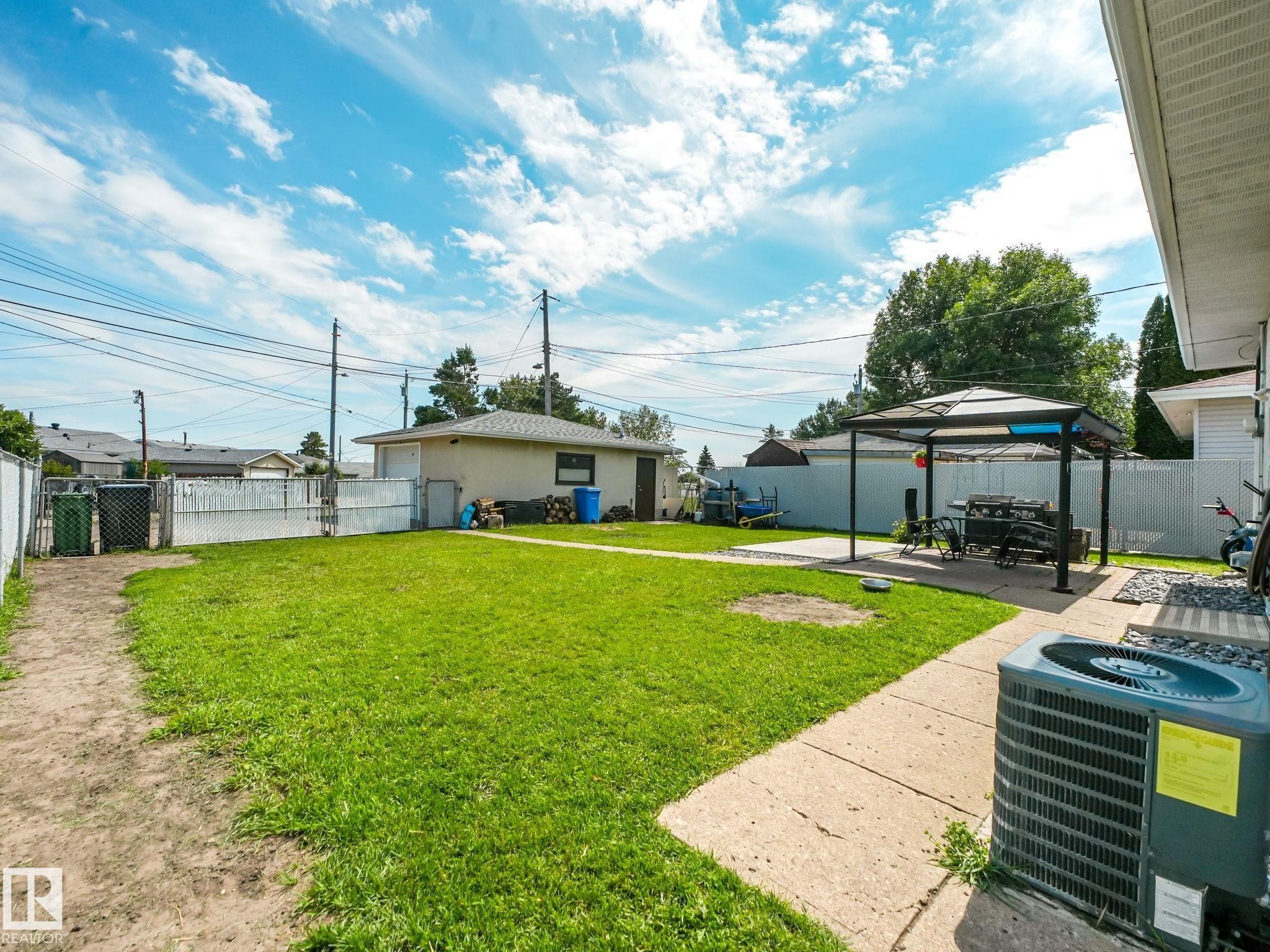 Spacious backyard featuring a manicured lawn, concrete patio, and detached garage - 13323 58 Street Nw, Edmonton, AB - Outdoor