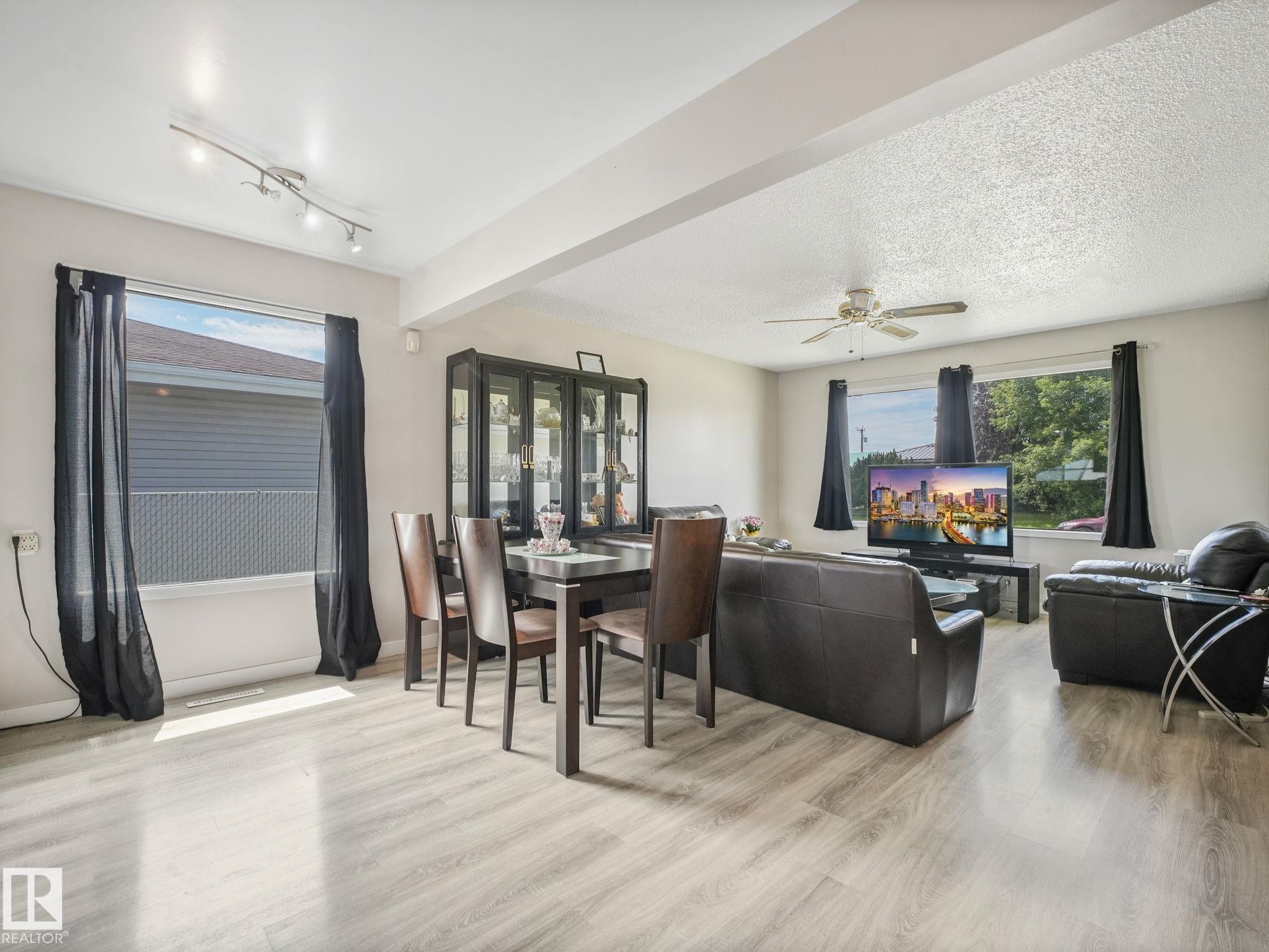 Open-concept living and dining area featuring wood-finish flooring and multiple windows - 13323 58 Street Nw, Edmonton, AB - Indoor