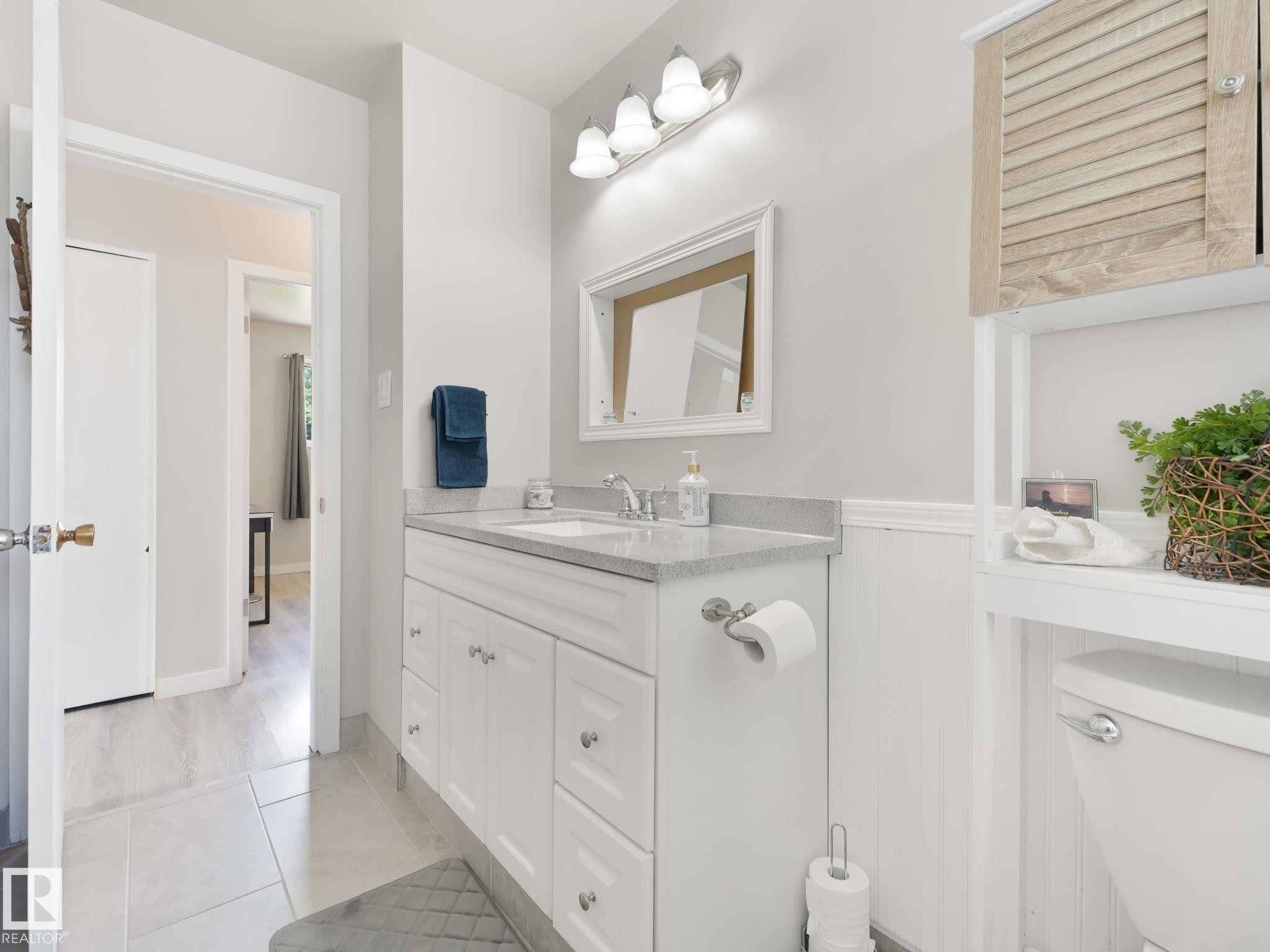 Bathroom featuring a white shaker-style vanity with a light-colored countertop, an undermount sink, and a chrome faucet - 13323 58 Street Nw, Edmonton, AB - Indoor Photo Showing Bathroom