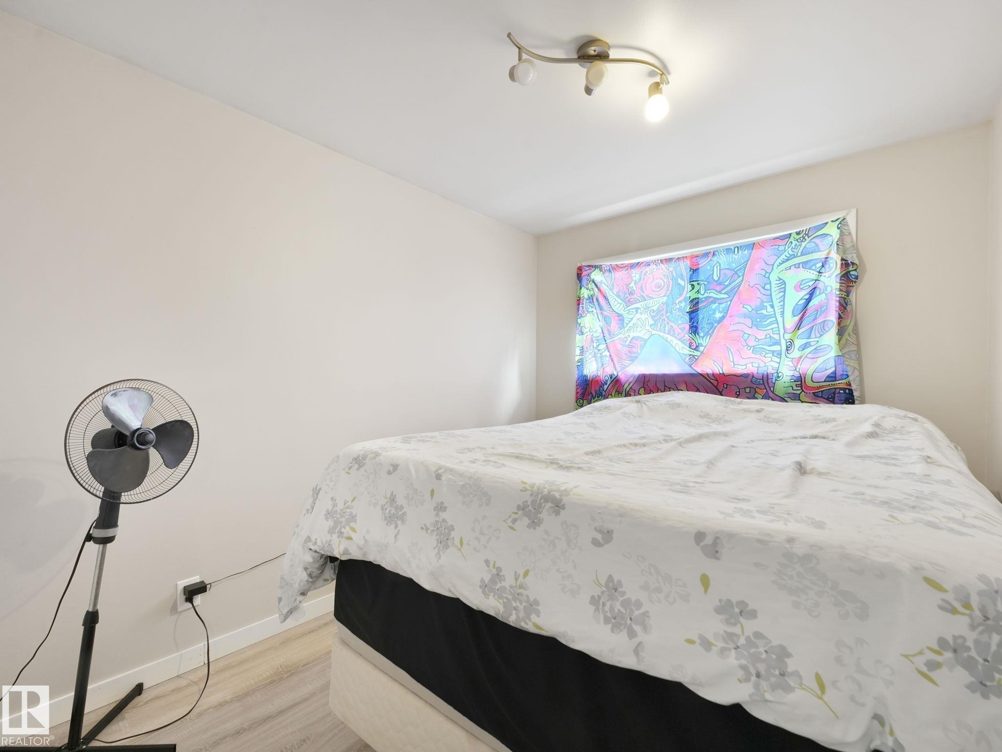 Neutral-toned walls complement wood-finish flooring - 13323 58 Street Nw, Edmonton, AB - Indoor Photo Showing Bedroom