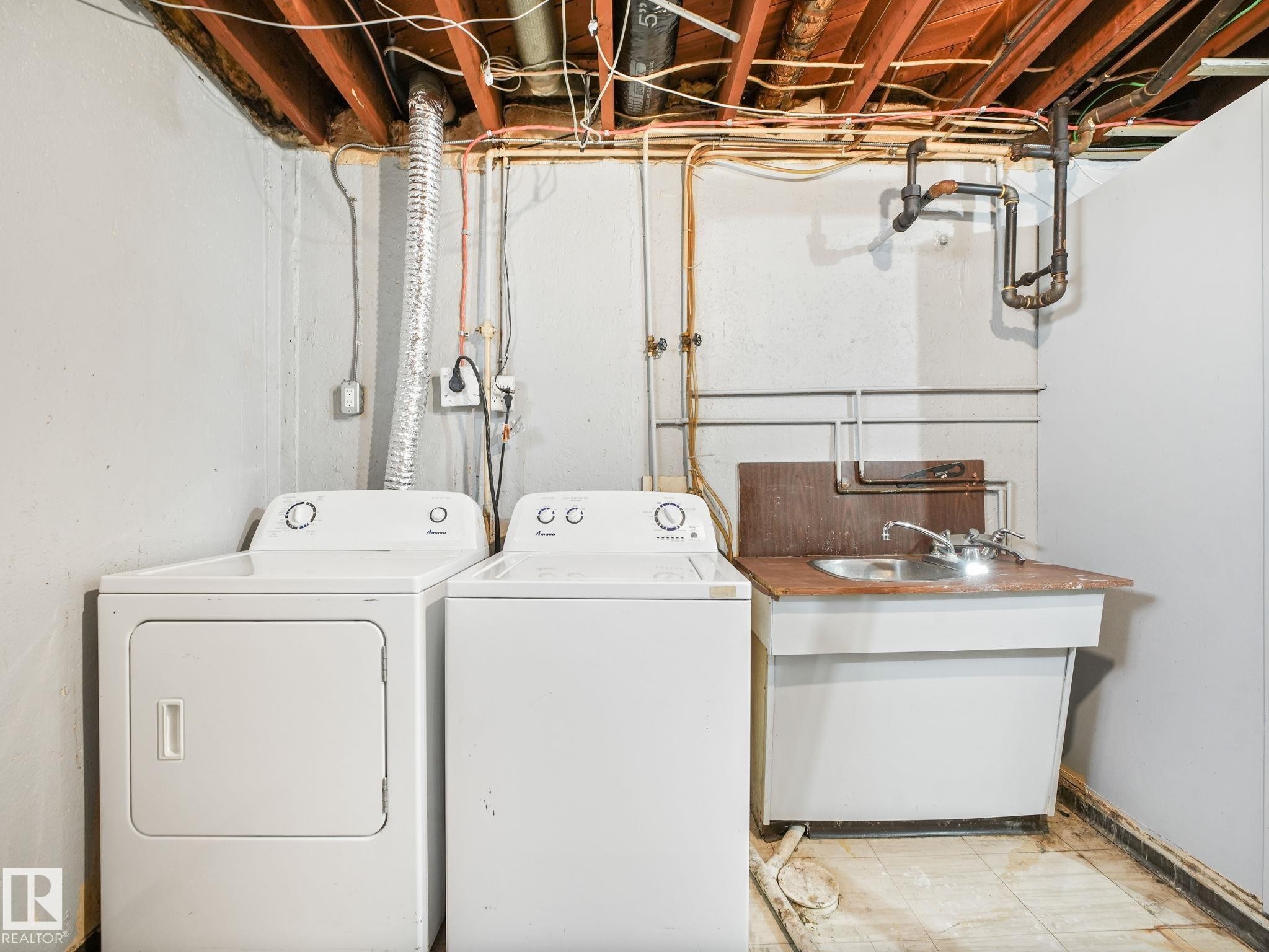 Laundry area with exposed ceiling joists, utility sink, and floor drain - 13323 58 Street Nw, Edmonton, AB - Indoor Photo Showing Laundry Room