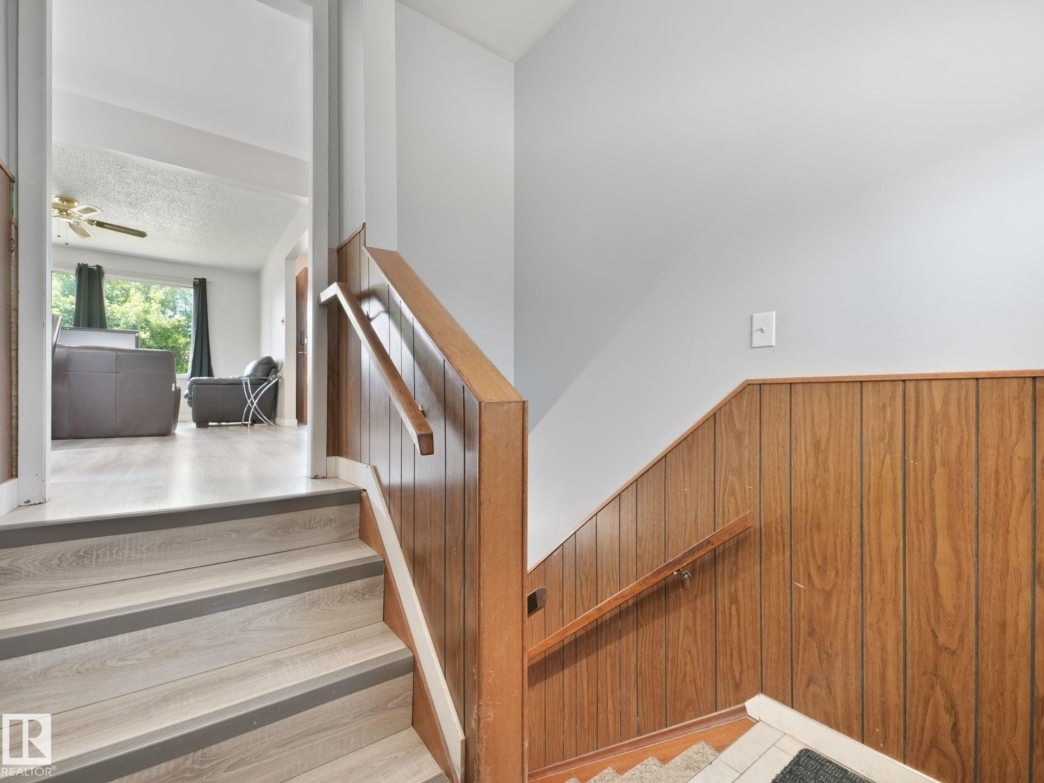 Split-level entry featuring wood-finish flooring on stairs and a wood-paneled wall - 13323 58 Street Nw, Edmonton, AB - Indoor Photo Showing Other Room
