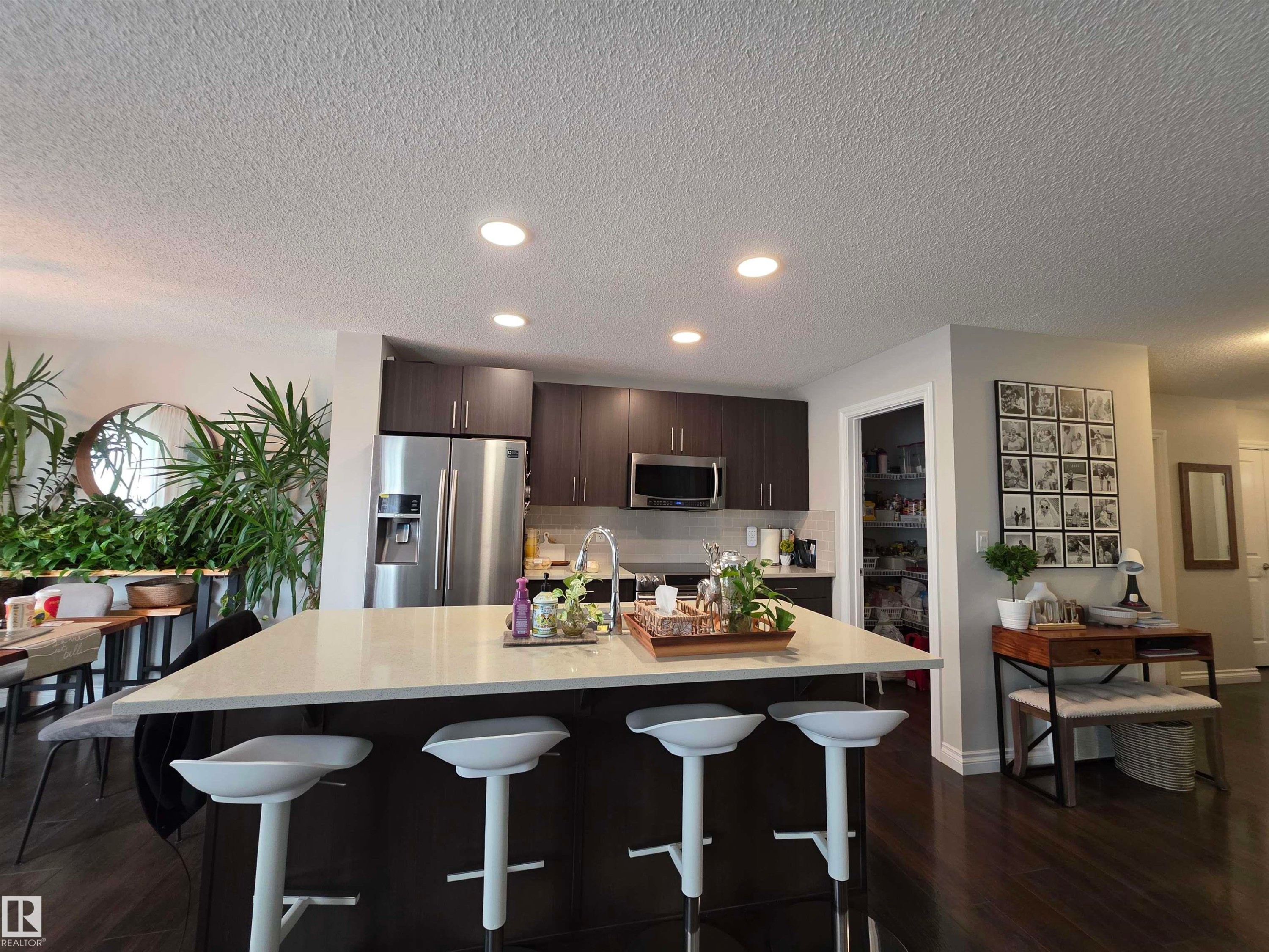 Kitchen island featuring a light-toned countertop with integrated seating for four - 491 Ebbers Way, Edmonton, AB