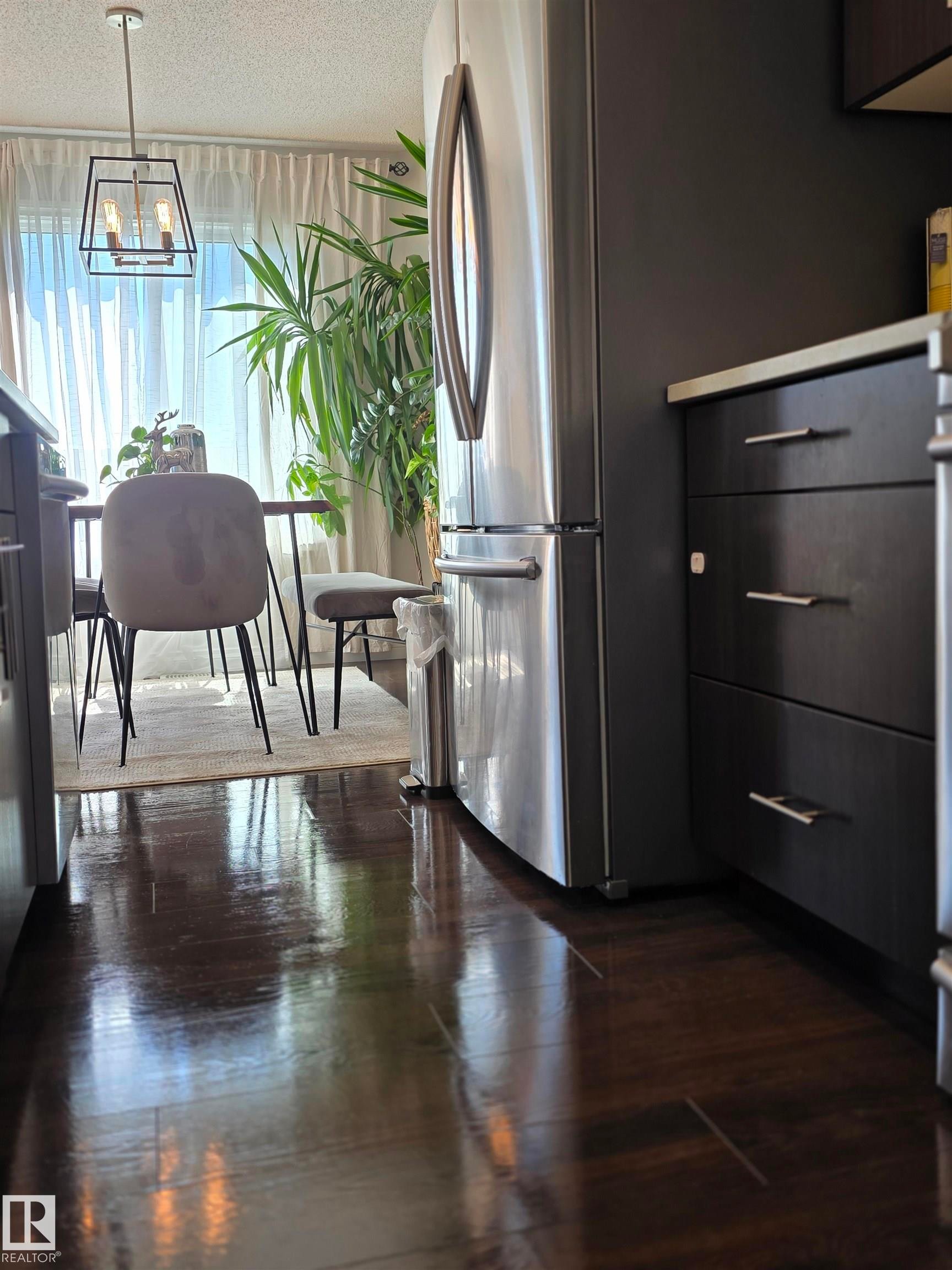 Stainless steel refrigerator and dark wood-finish cabinetry with silver hardware - 491 Ebbers Way, Edmonton, AB