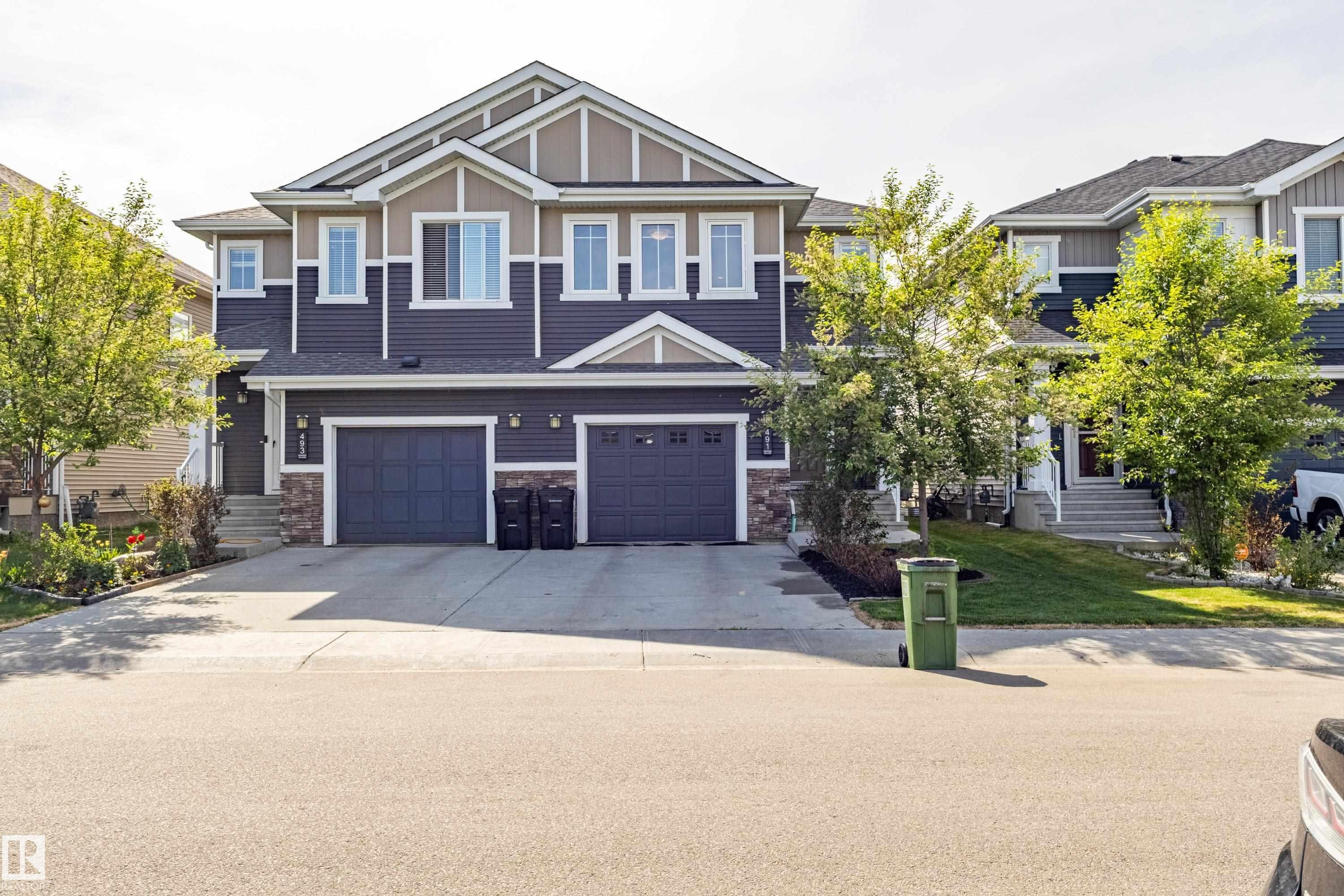 Contemporary facade featuring dark blue siding, tan accents, and stone detailing - 491 Ebbers Way, Edmonton, AB