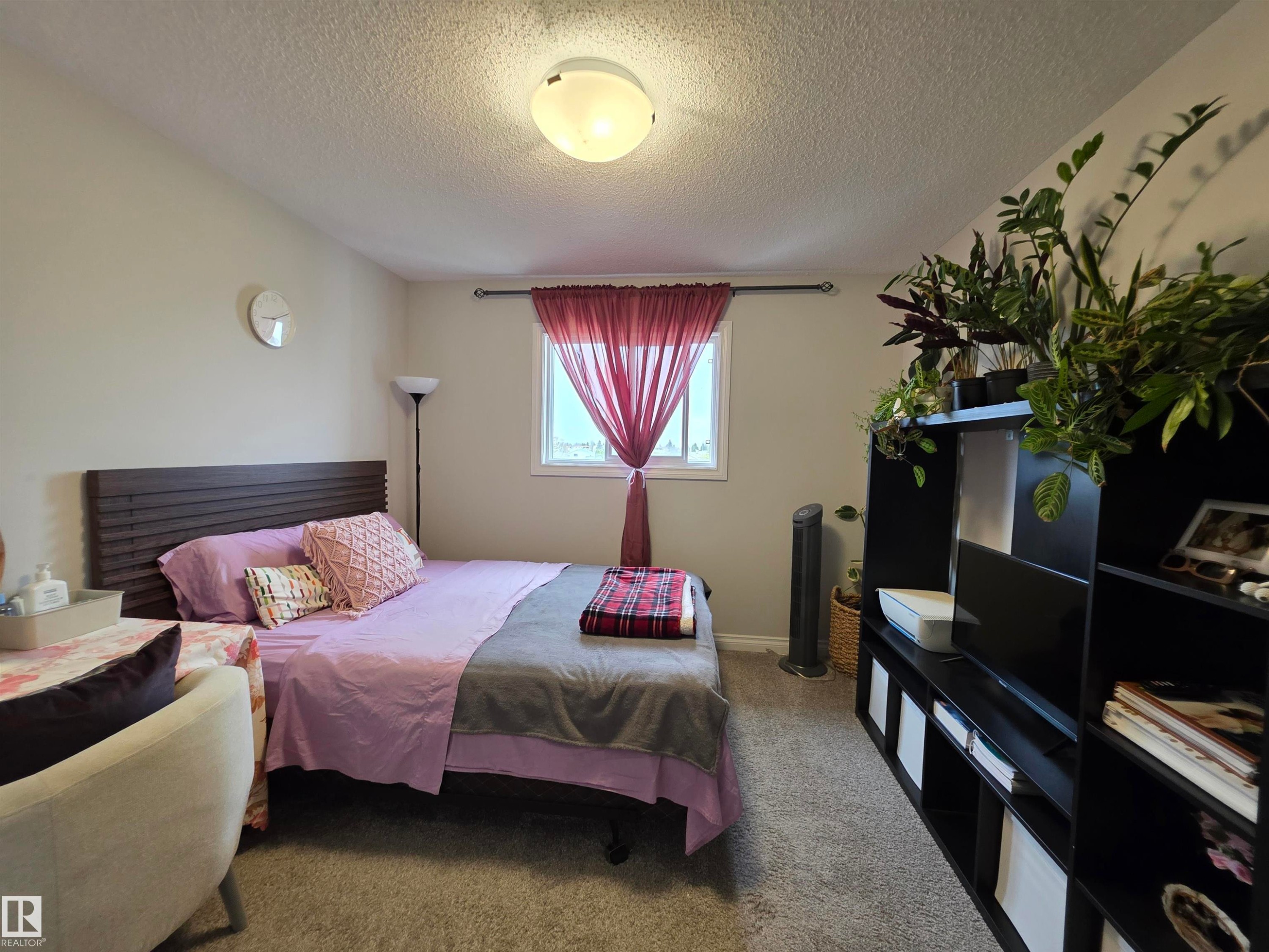 Carpeted bedroom featuring a textured headboard, a window with natural light, and a ceiling-mounted light fixture - 491 Ebbers Way, Edmonton, AB
