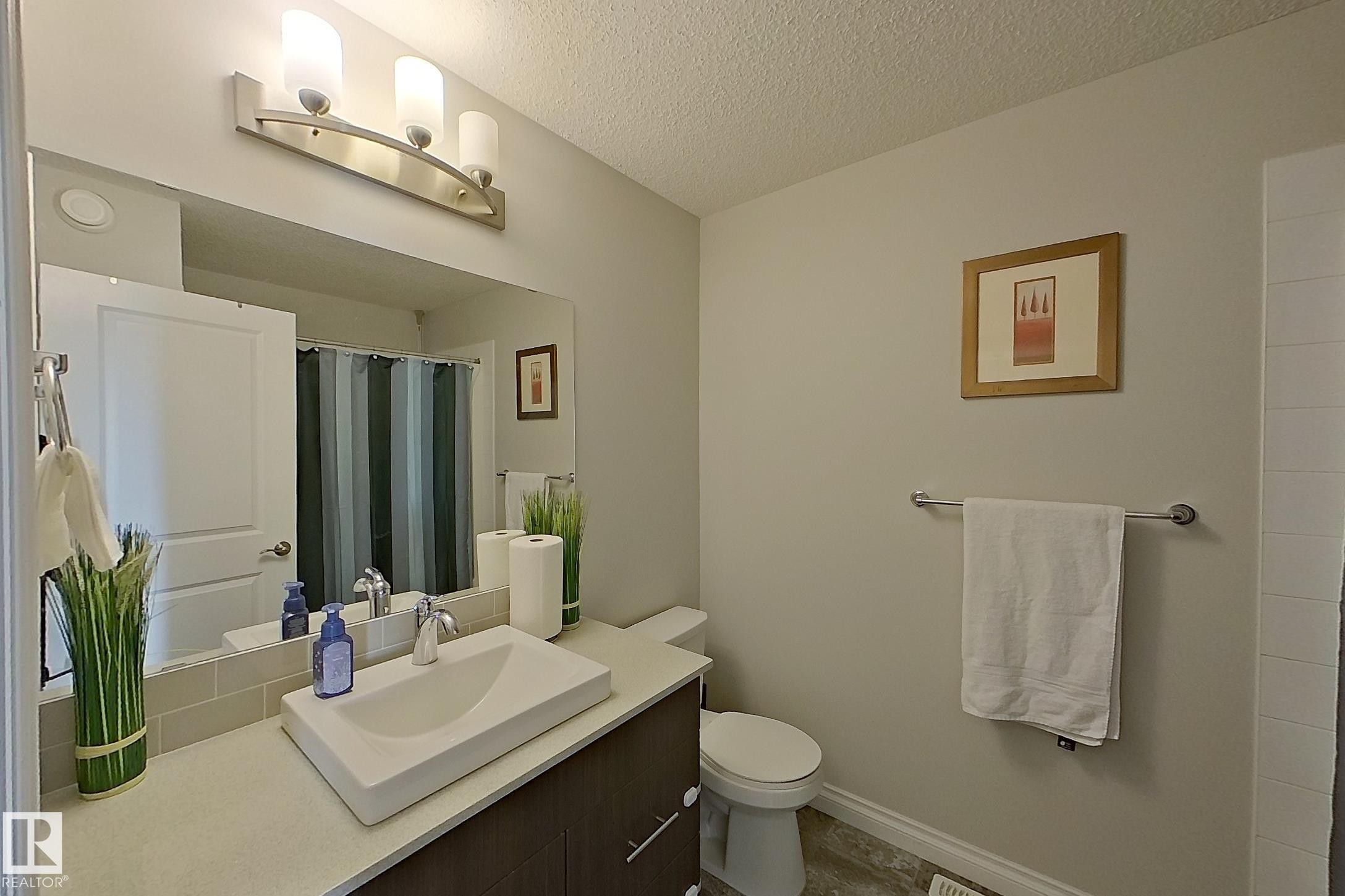 Contemporary vanity featuring a rectangular vessel sink with chrome faucet, complemented by a large wall-mounted mirror - 491 Ebbers Way, Edmonton, AB