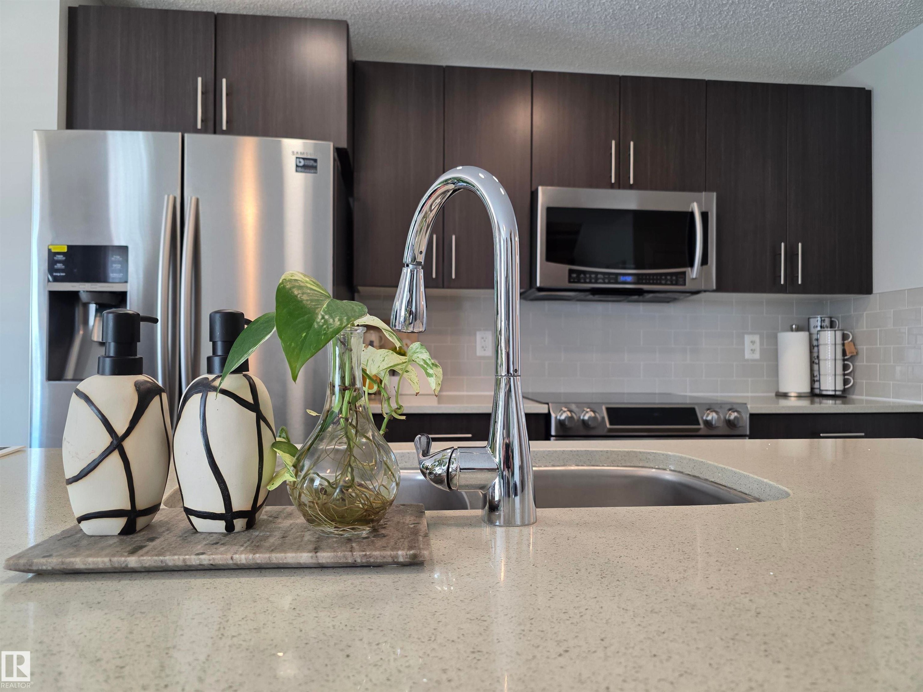 Contemporary kitchen featuring dark wood-finish cabinetry and light-toned countertops - 491 Ebbers Way, Edmonton, AB