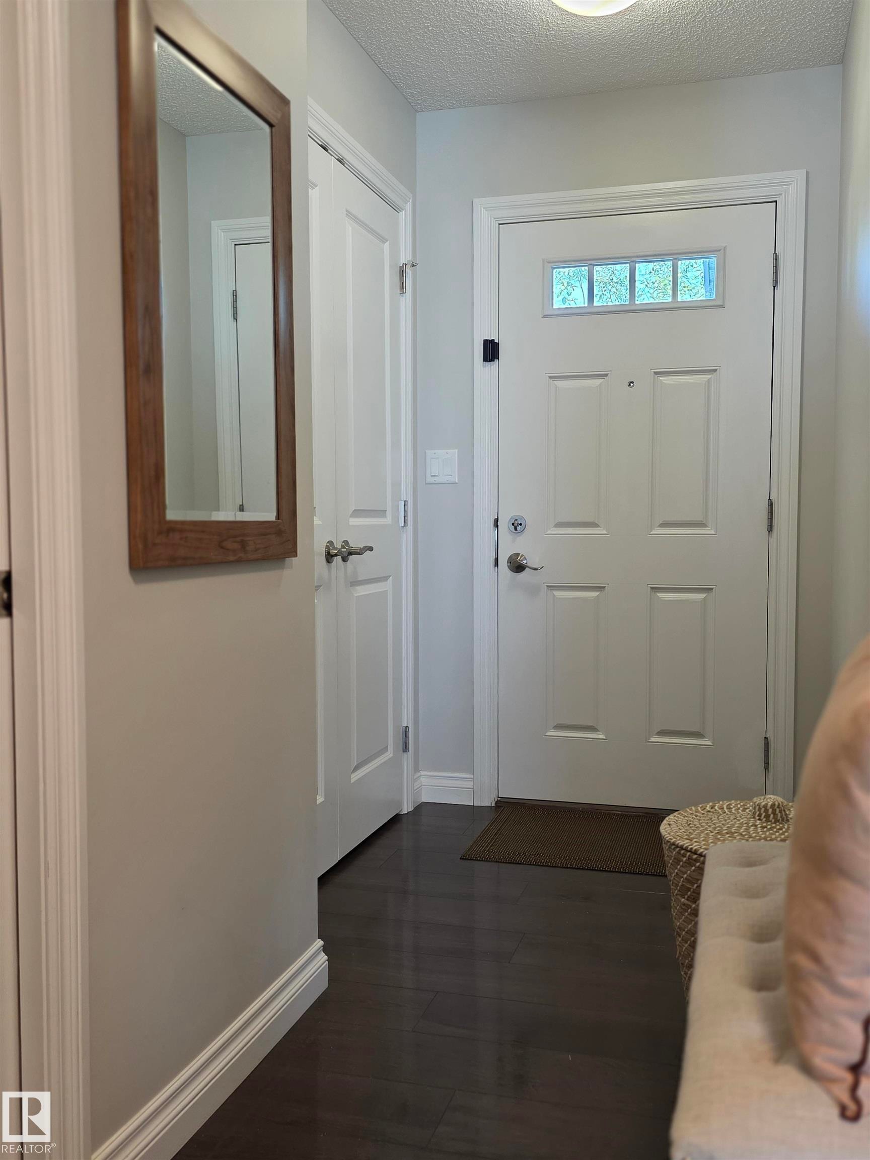 Entryway featuring dark wood-finish flooring and a white paneled front door with a transom window - 491 Ebbers Way, Edmonton, AB