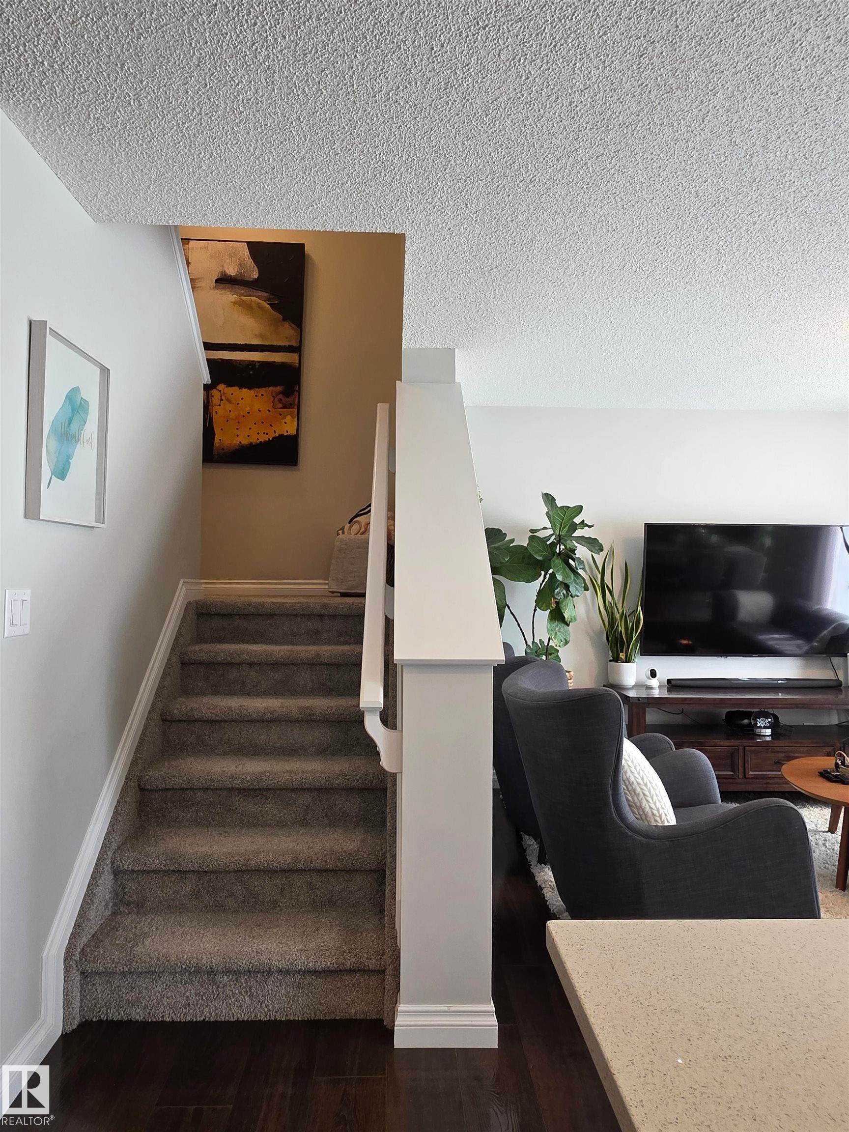 Carpeted staircase featuring white balustrade and handrail - 491 Ebbers Way, Edmonton, AB
