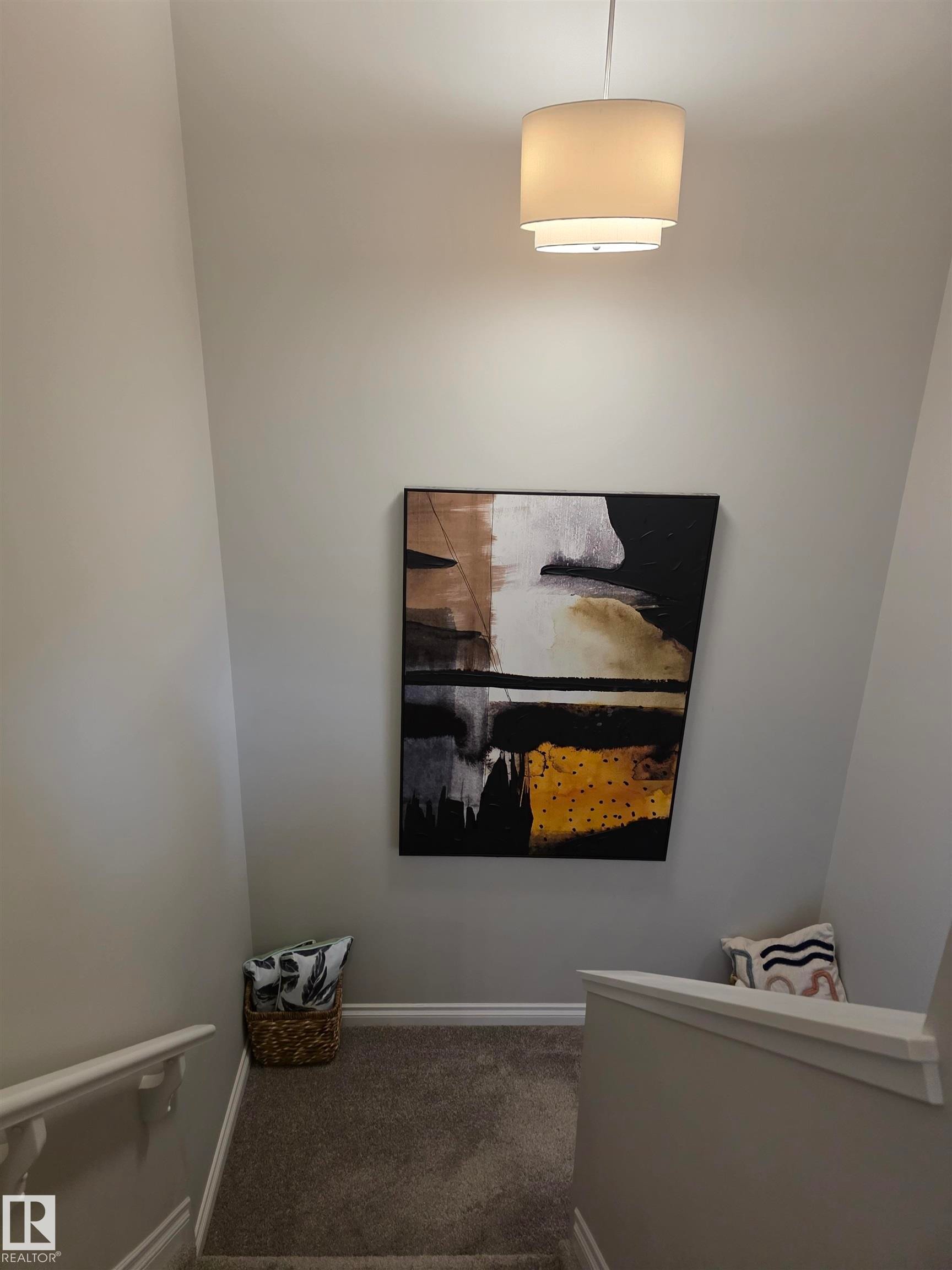 Staircase with plush carpet flooring, white painted handrails, and a contemporary drum pendant light fixture - 491 Ebbers Way, Edmonton, AB
