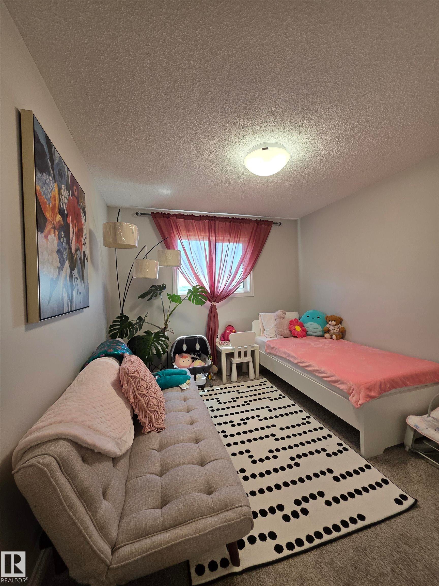 Room featuring neutral wall paint, a window with red sheer curtains, and a flush-mount ceiling light fixture - 491 Ebbers Way, Edmonton, AB