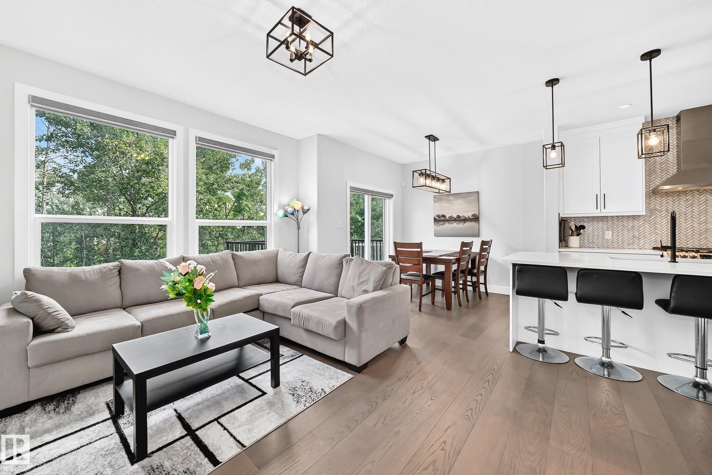 Open-concept living space featuring wood-finish flooring, white walls, and a modern kitchen - 22270 99A Avenue Nw, Edmonton, AB - Indoor Photo Showing Living Room