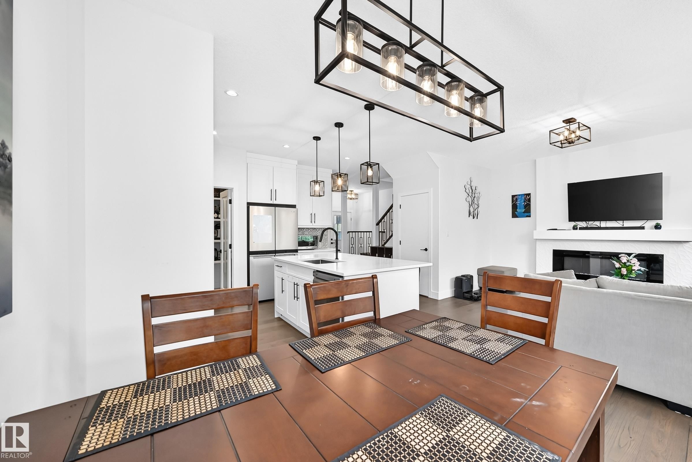 Open-concept living area featuring a formal dining space, kitchen island, and contemporary fireplace - 22270 99A Avenue Nw, Edmonton, AB - Indoor Photo Showing Other Room