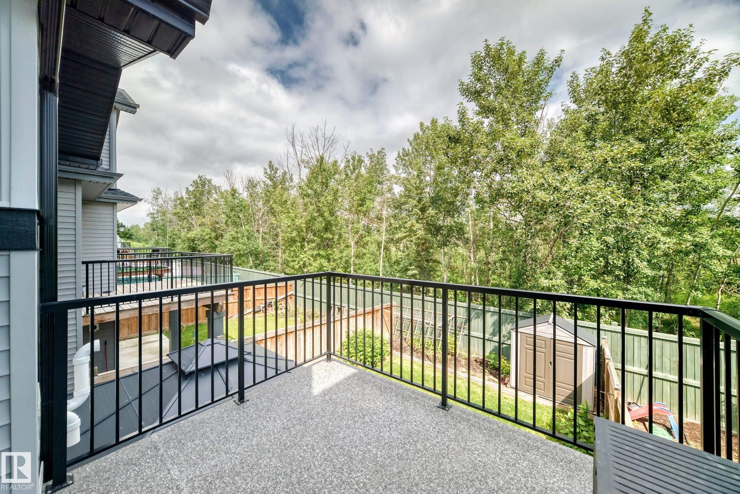 Spacious outdoor balcony with a textured concrete surface and contemporary black metal railings - 22270 99A Avenue Nw, Edmonton, AB - Outdoor With Exterior
