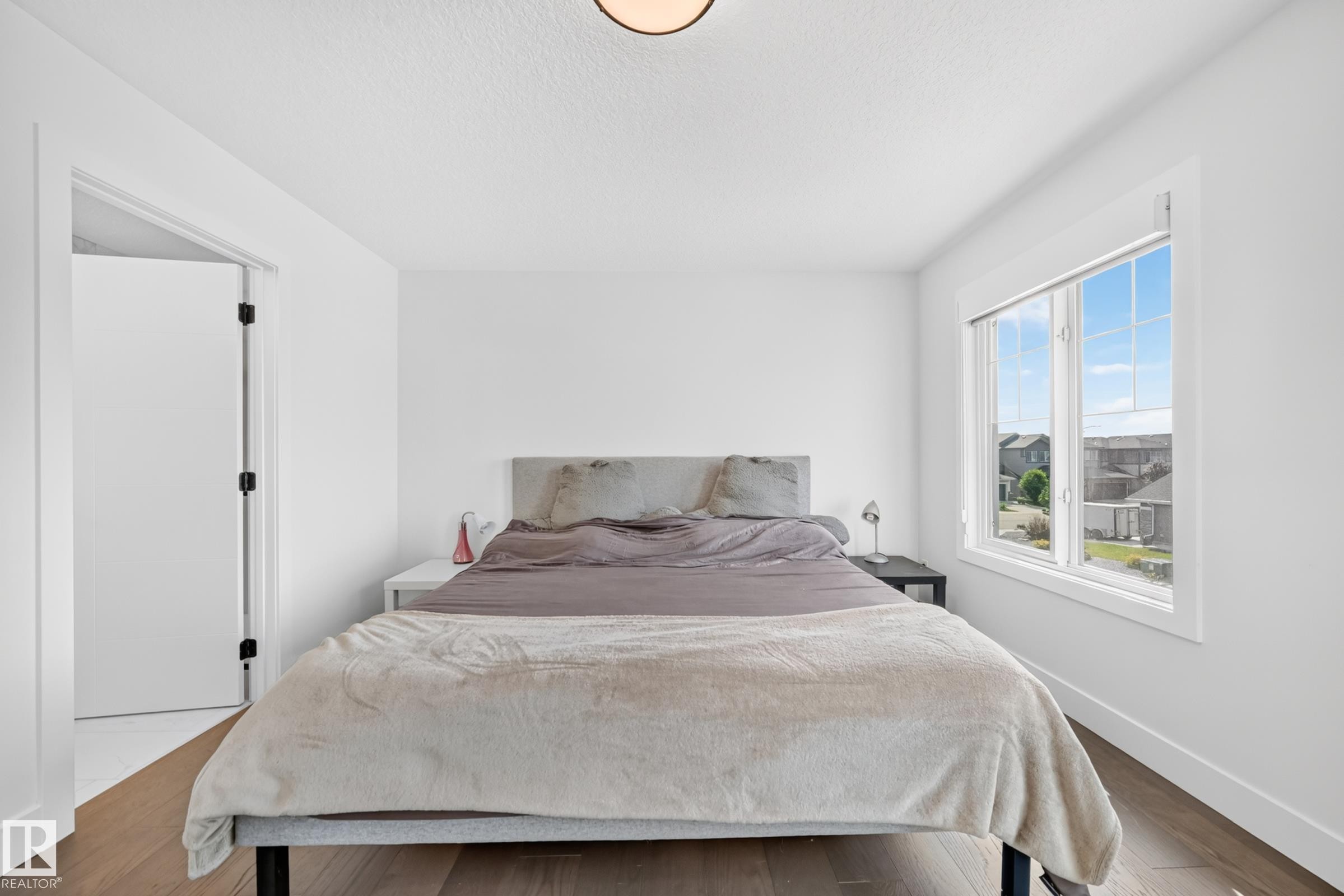 Bedroom featuring wood-finish flooring and a large window with white trim - 22270 99A Avenue Nw, Edmonton, AB - Indoor Photo Showing Bedroom