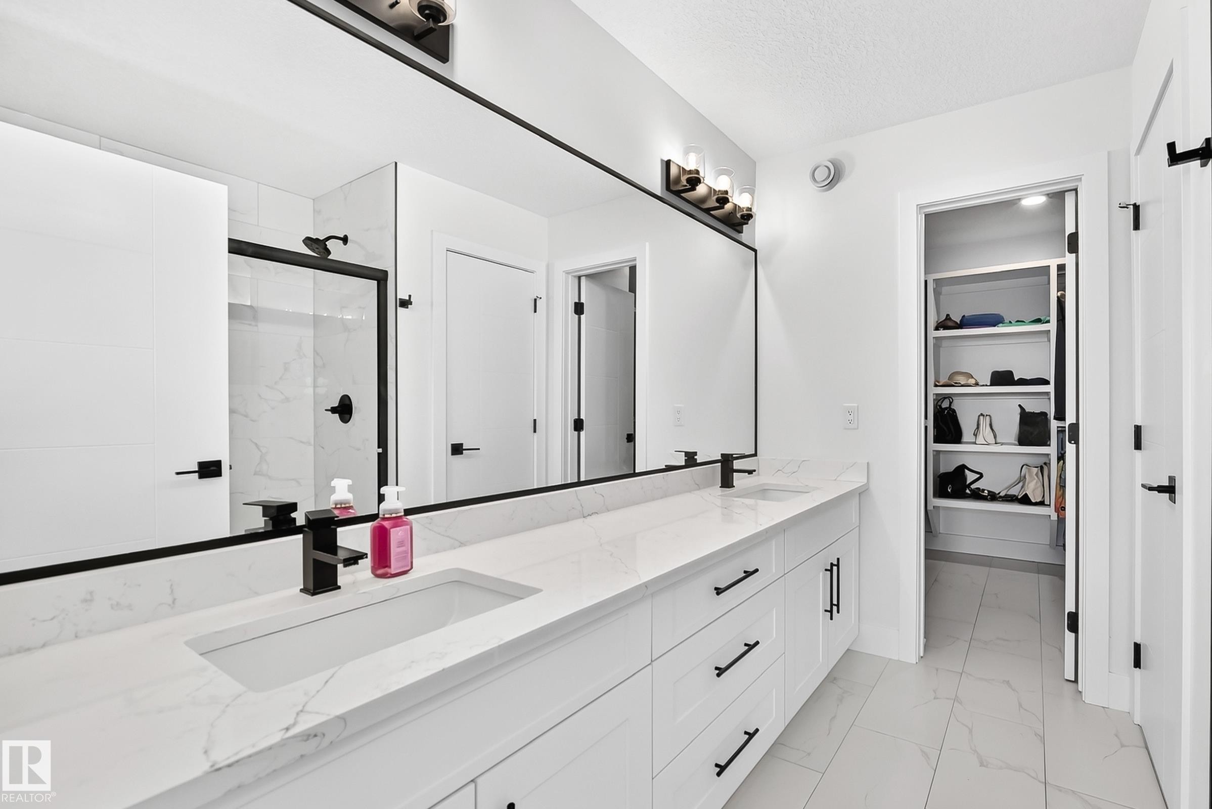 Contemporary bathroom featuring a large double vanity with integrated sinks, white cabinetry, and a full-width mirror - 22270 99A Avenue Nw, Edmonton, AB - Indoor