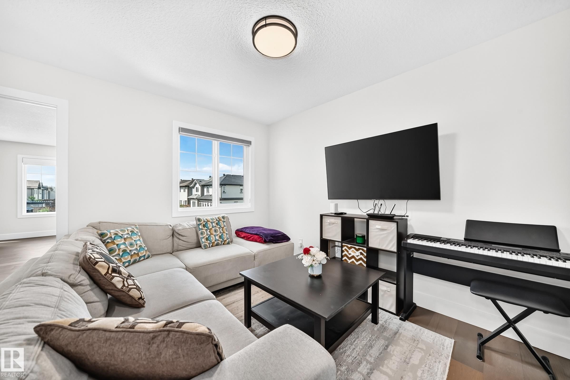 Living area with wood-finish flooring, white walls, and a large window - 22270 99A Avenue Nw, Edmonton, AB - Indoor Photo Showing Living Room