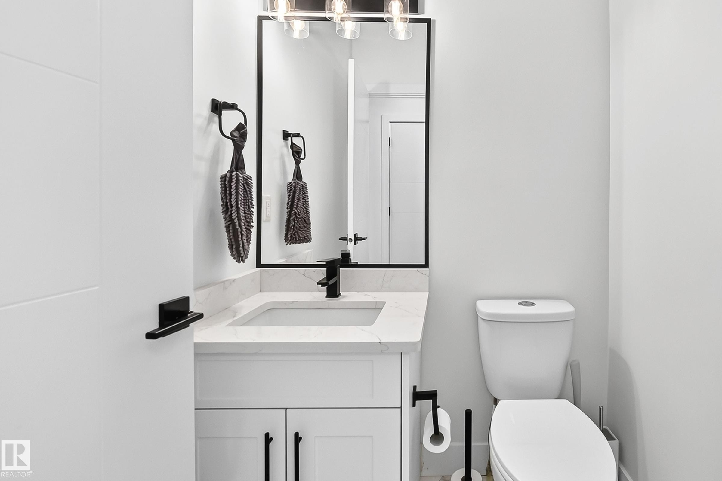 Bathroom featuring a white vanity with a rectangular sink, a light-colored countertop, and a matte black faucet - 22270 99A Avenue Nw, Edmonton, AB - Indoor Photo Showing Bathroom