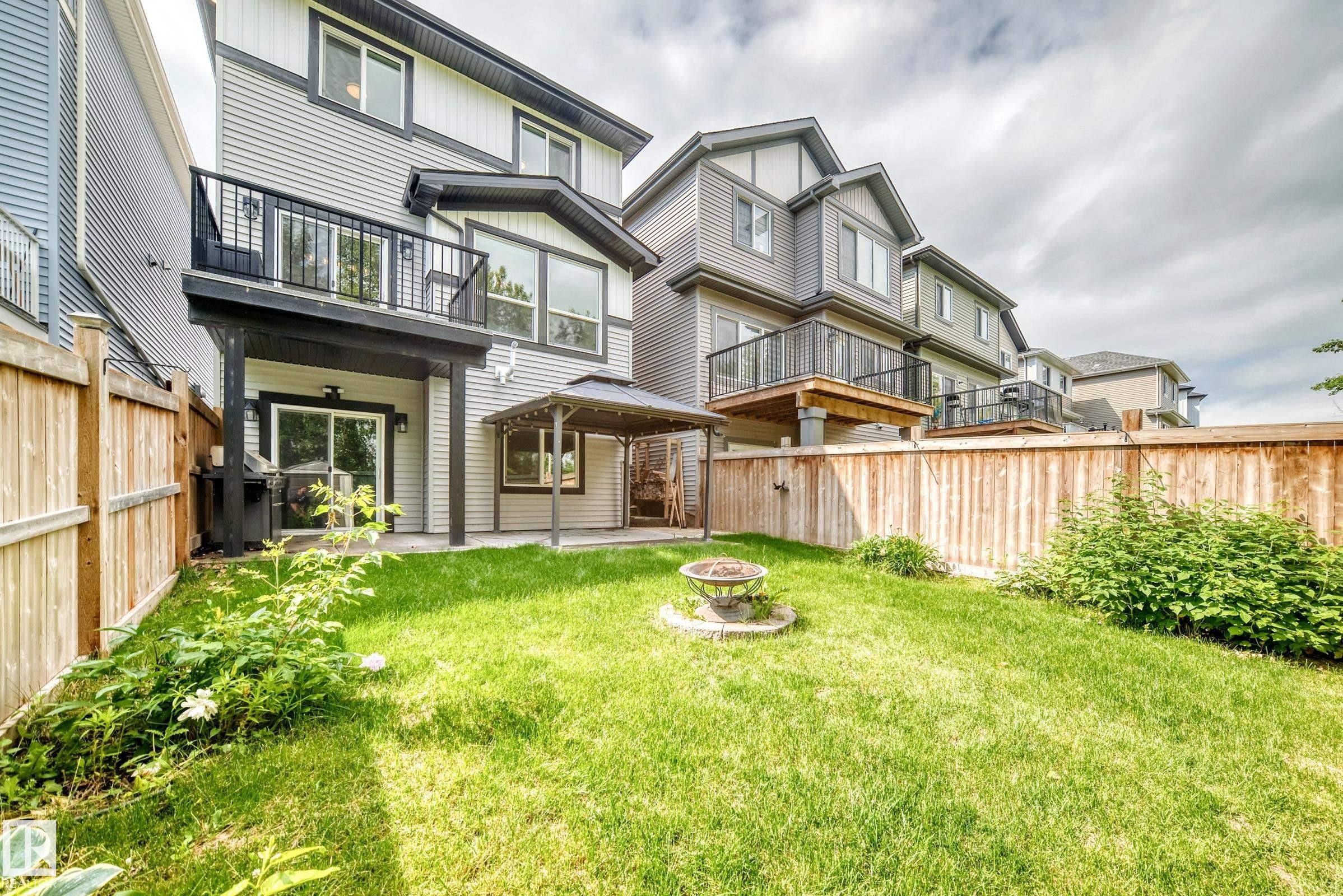 Expansive green lawn with a fire pit feature, surrounded by a wooden fence - 22270 99A Avenue Nw, Edmonton, AB - Outdoor