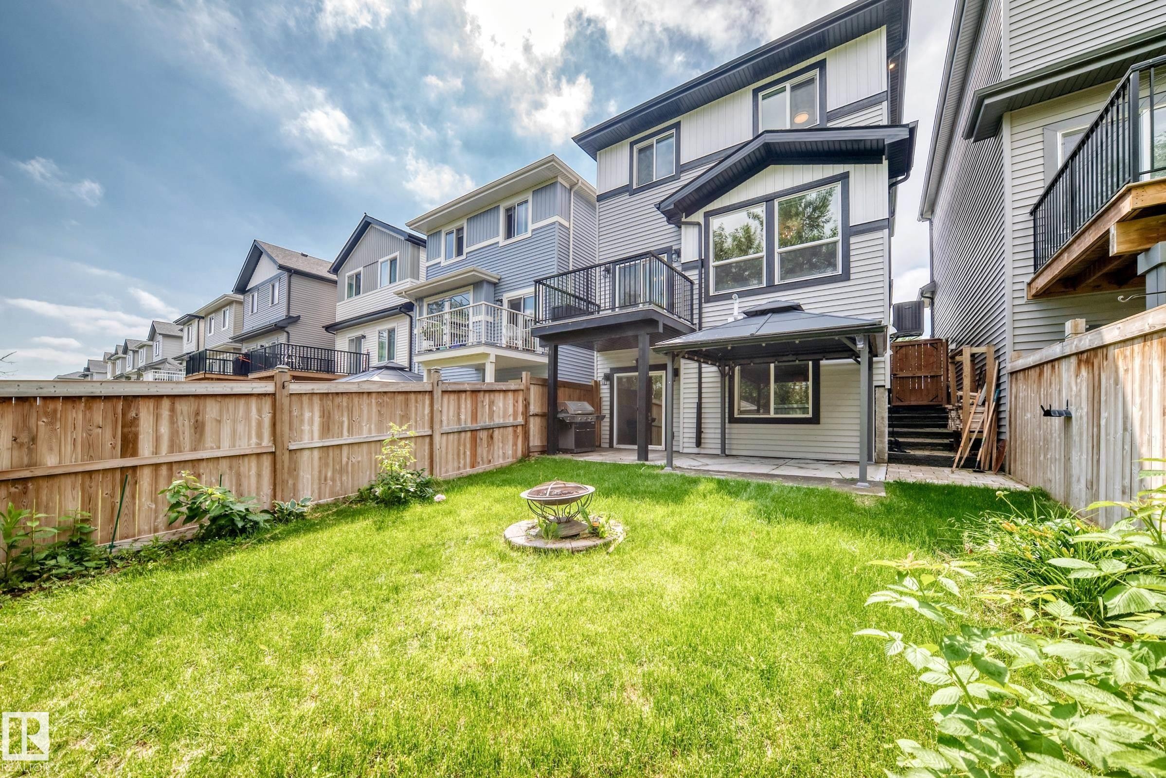 Expansive backyard featuring a manicured lawn, a fire pit, and a covered patio area with a gazebo - 22270 99A Avenue Nw, Edmonton, AB - Outdoor