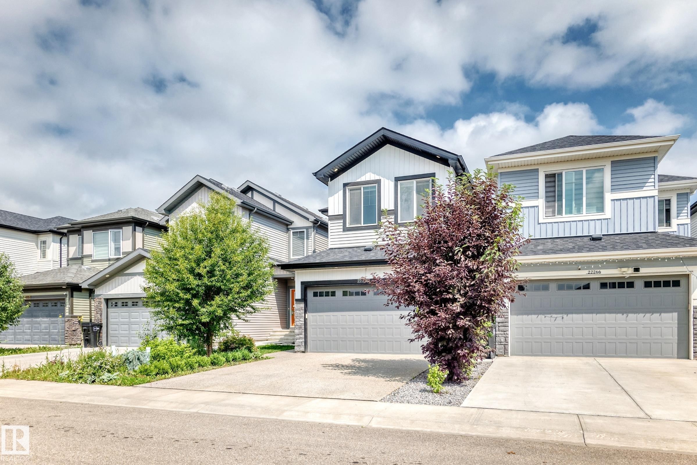 Modern facade featuring horizontal and vertical siding, a two-car garage, and established landscaping - 22270 99A Avenue Nw, Edmonton, AB - Outdoor With Facade