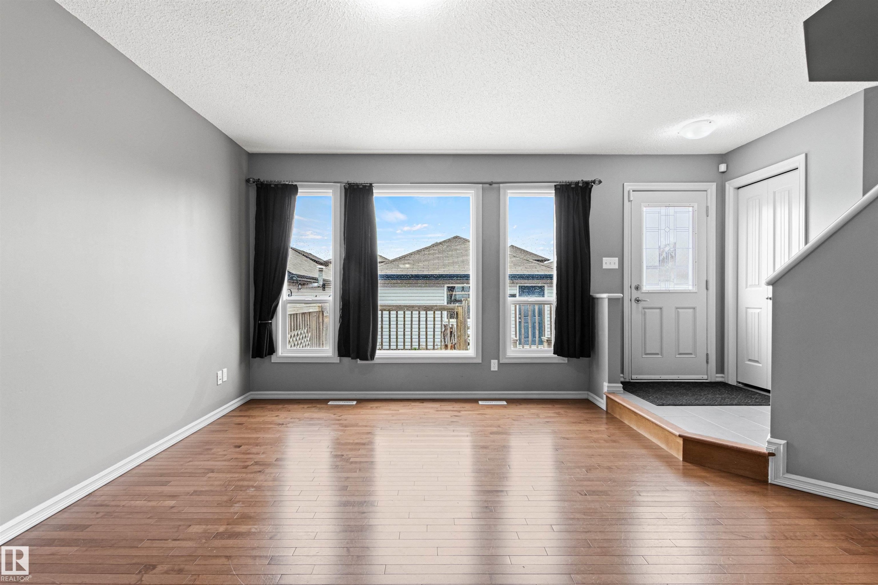 Open-concept living area with wood-finish flooring, light gray walls, and white trim - 1154 35A Avenue Nw, Edmonton, AB - Indoor Photo Showing Other Room