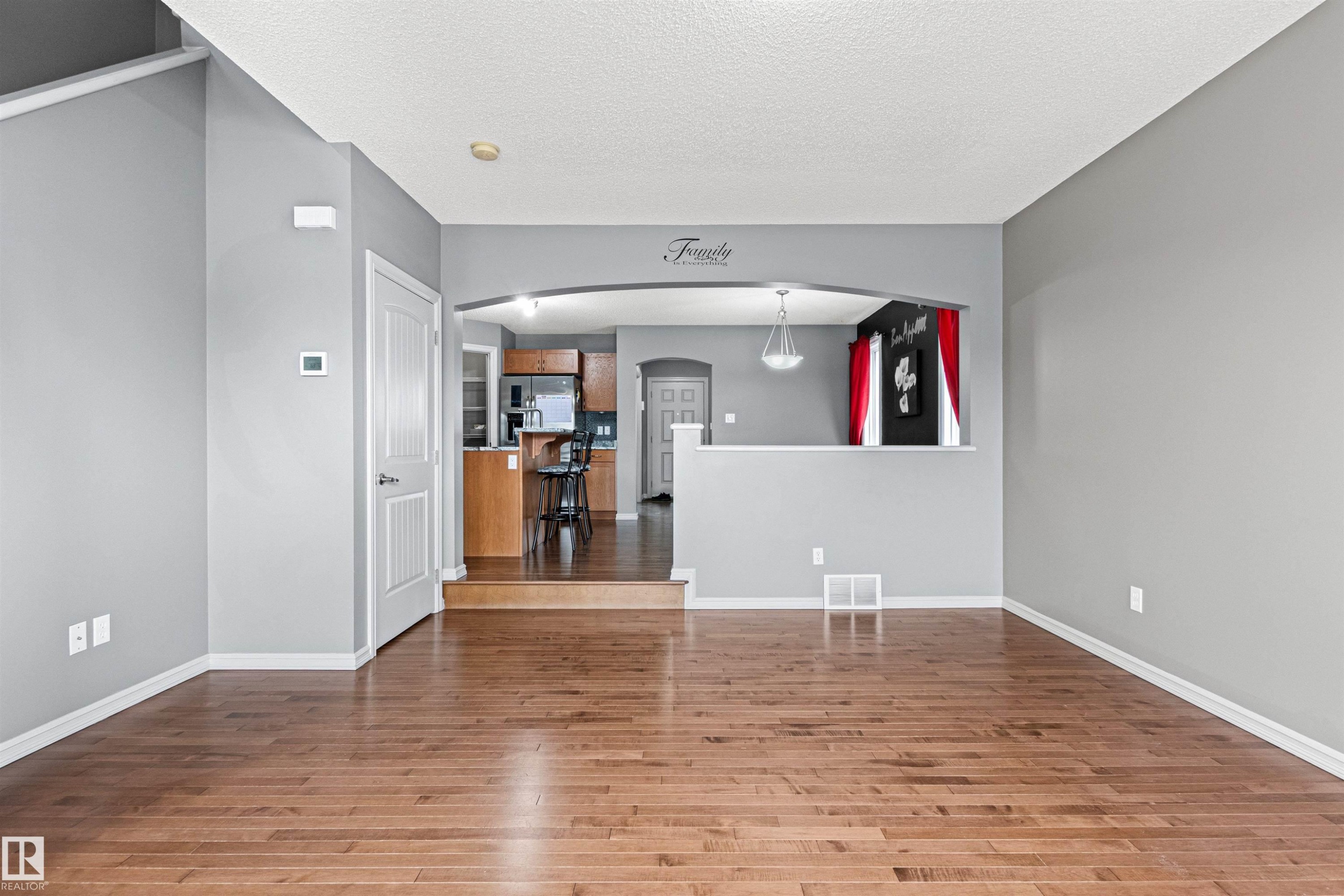 Expansive room with wood-finish flooring, light grey walls, and white trim - 1154 35A Avenue Nw, Edmonton, AB - Indoor Photo Showing Other Room