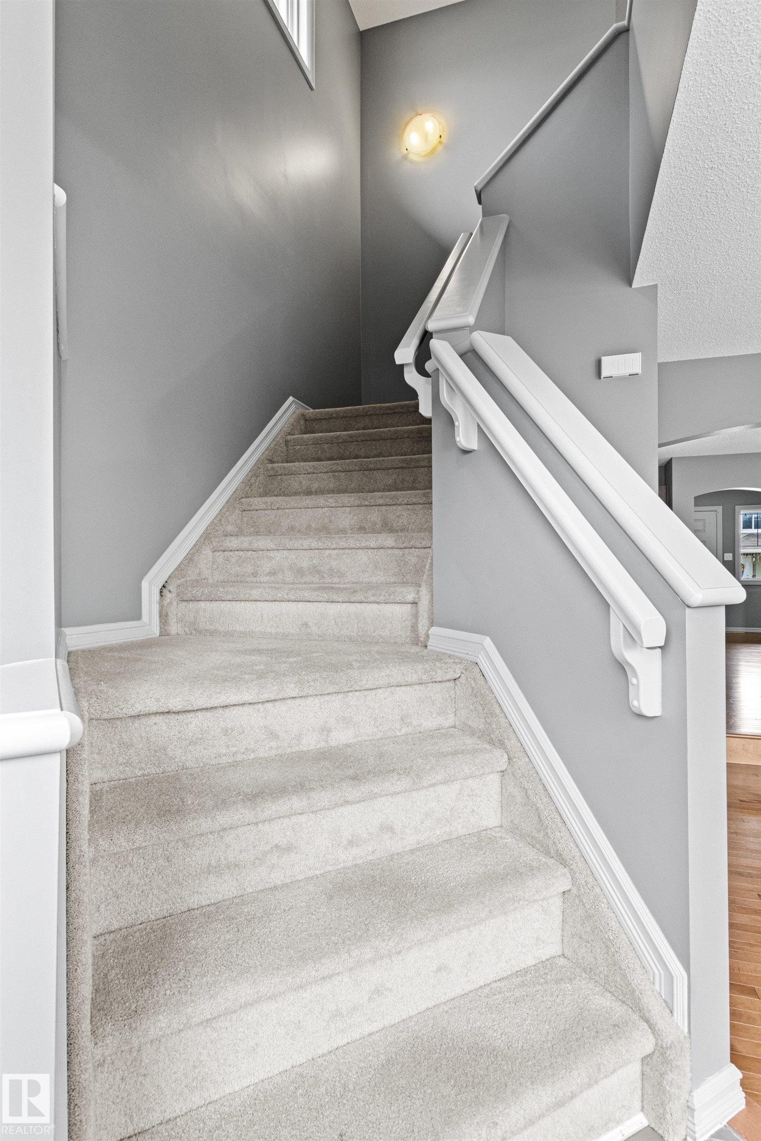 Carpeted staircase with white handrails and painted gray walls - 1154 35A Avenue Nw, Edmonton, AB - Indoor Photo Showing Other Room