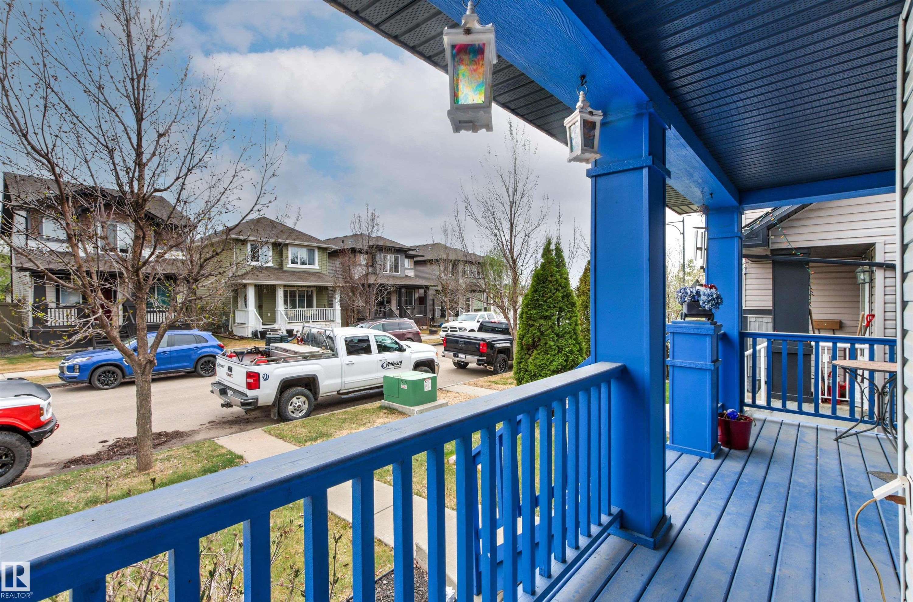 Covered front porch featuring a vibrant blue finish on the floorboards, railings, and support columns - 1154 35A Avenue Nw, Edmonton, AB - Outdoor With Deck Patio Veranda