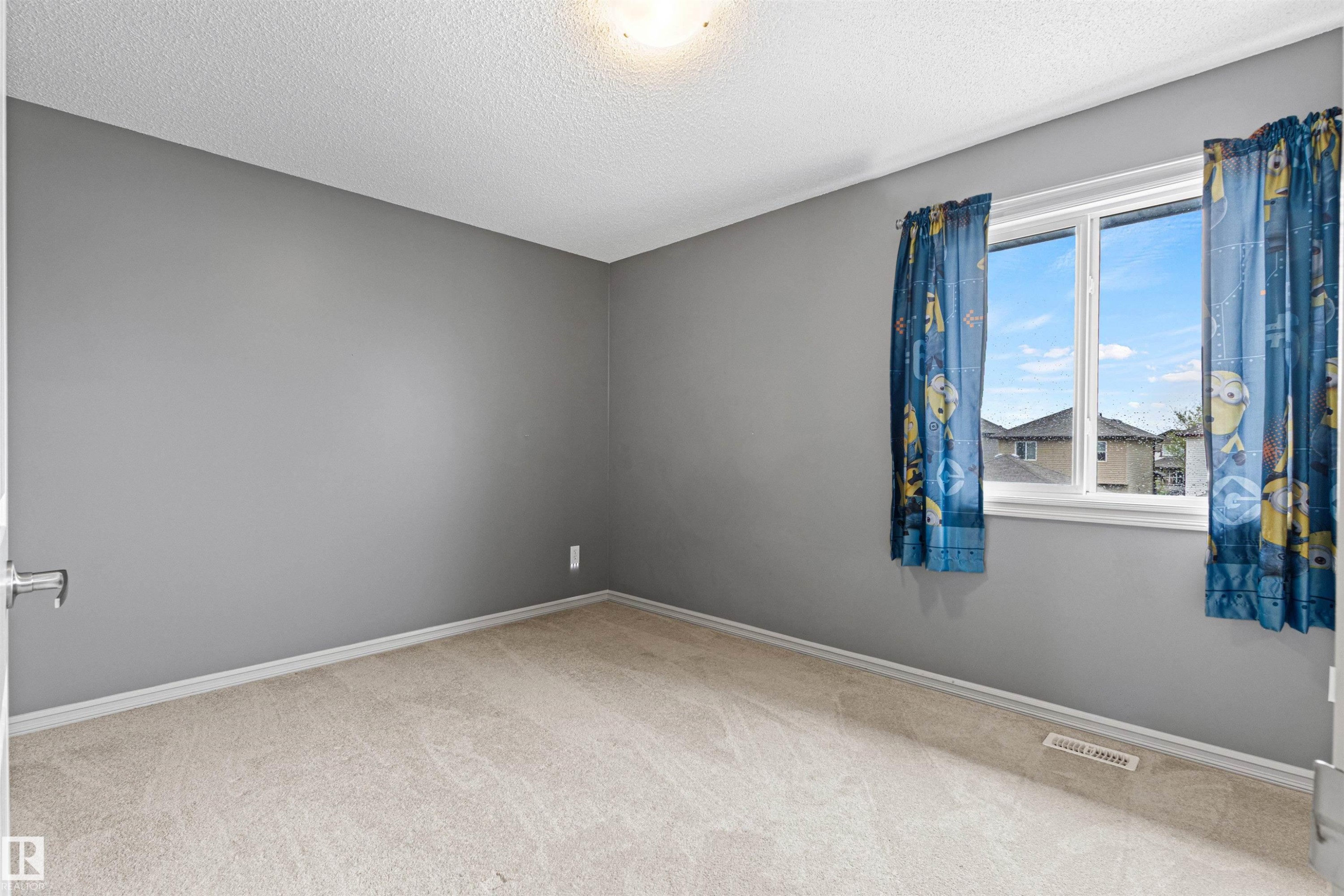 Carpeted room featuring neutral gray walls, a textured ceiling, white trim, and a window providing natural light - 1154 35A Avenue Nw, Edmonton, AB - Indoor Photo Showing Other Room