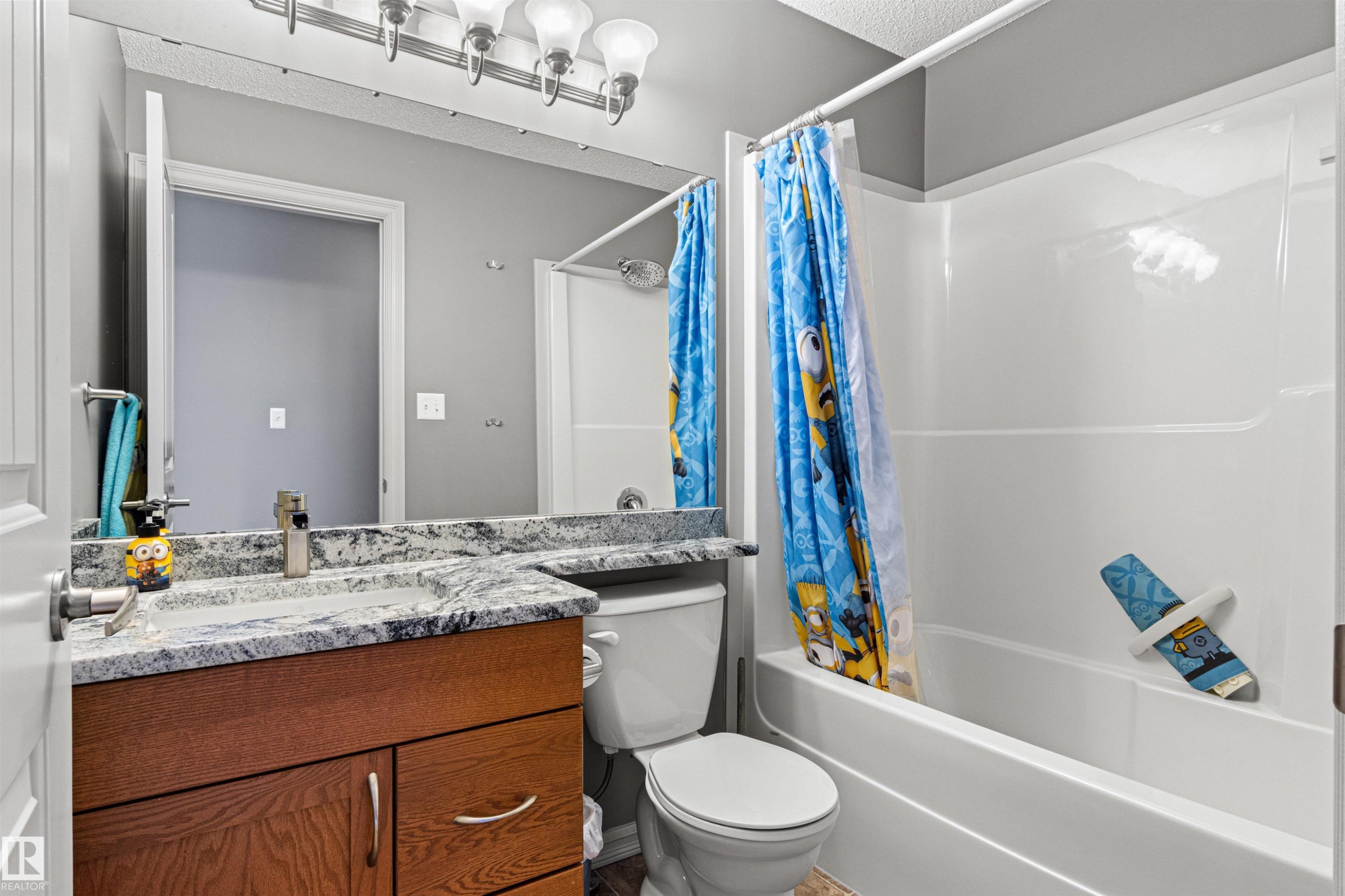 Bathroom featuring a wood-finish vanity with a granite-style countertop, undermount sink, and chrome faucet - 1154 35A Avenue Nw, Edmonton, AB - Indoor Photo Showing Bathroom