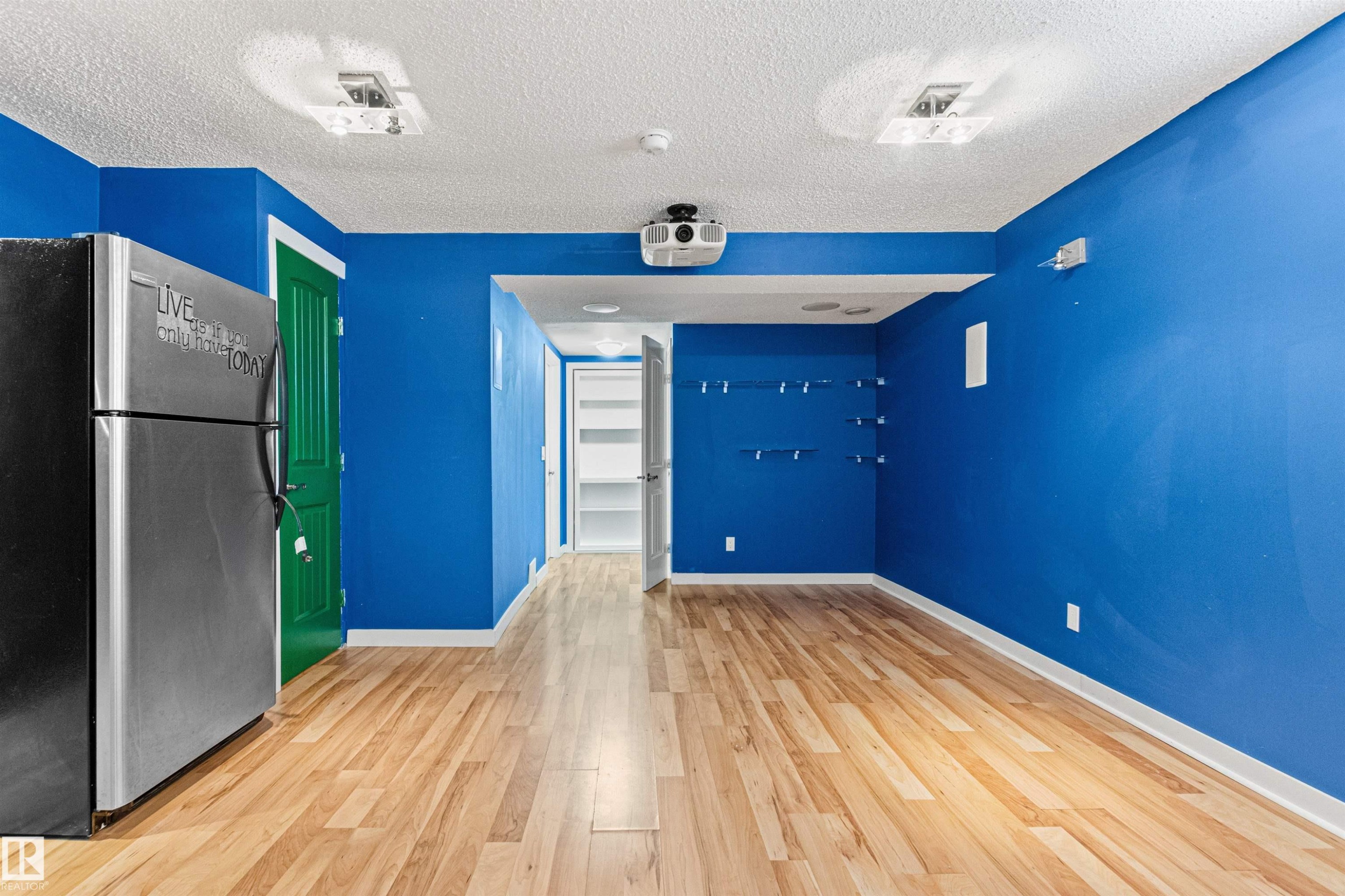Spacious room with wood-finish flooring, vibrant blue walls, and recessed lighting - 1154 35A Avenue Nw, Edmonton, AB - Indoor Photo Showing Other Room